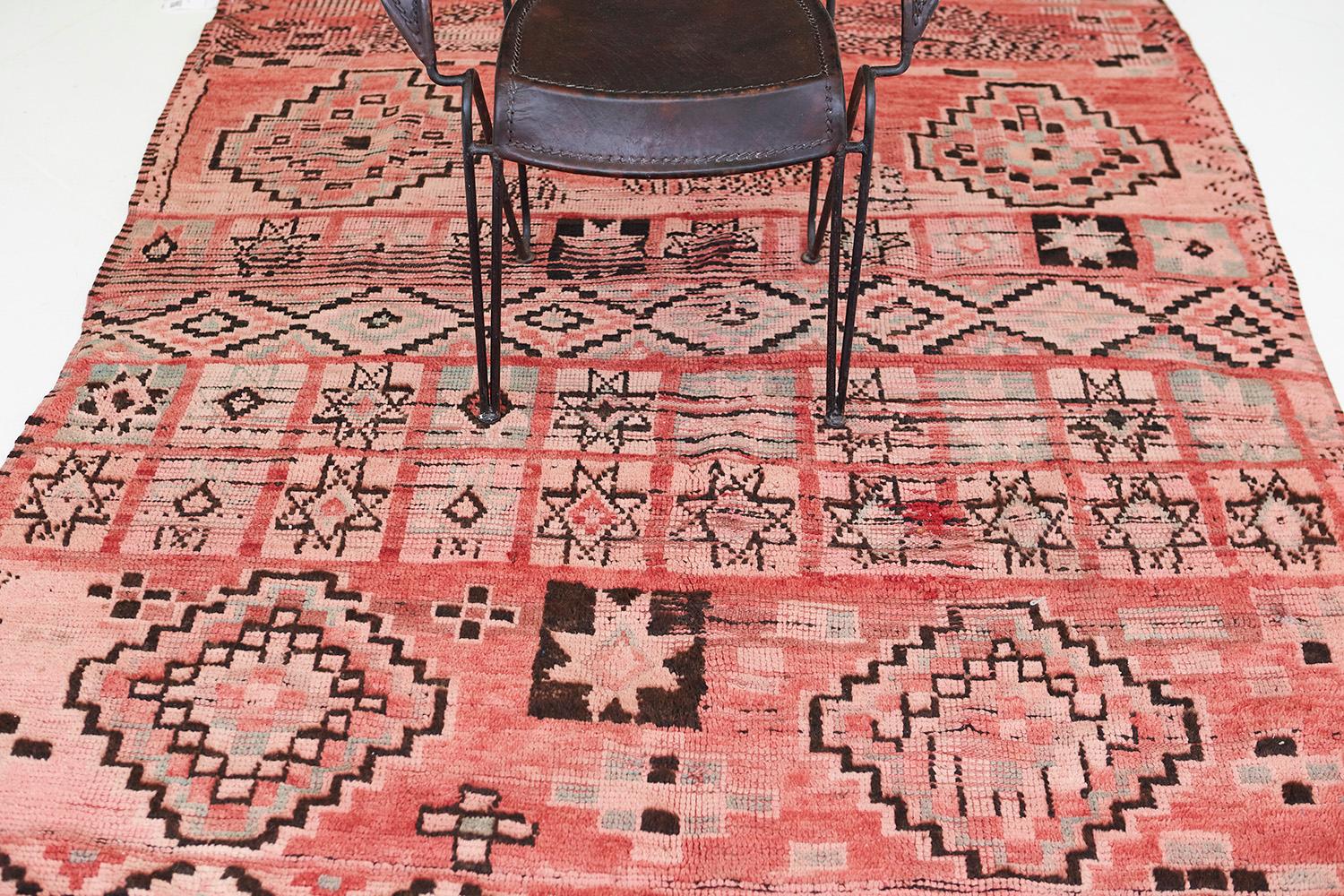 A vintage Moroccan Azilal Tribe Berber rug that features symbols that highlights the significance of patterns woven into this magnificent rug. It boasts a series of zigzag lines that form together and are eventually bounded by lozenge trellis and
