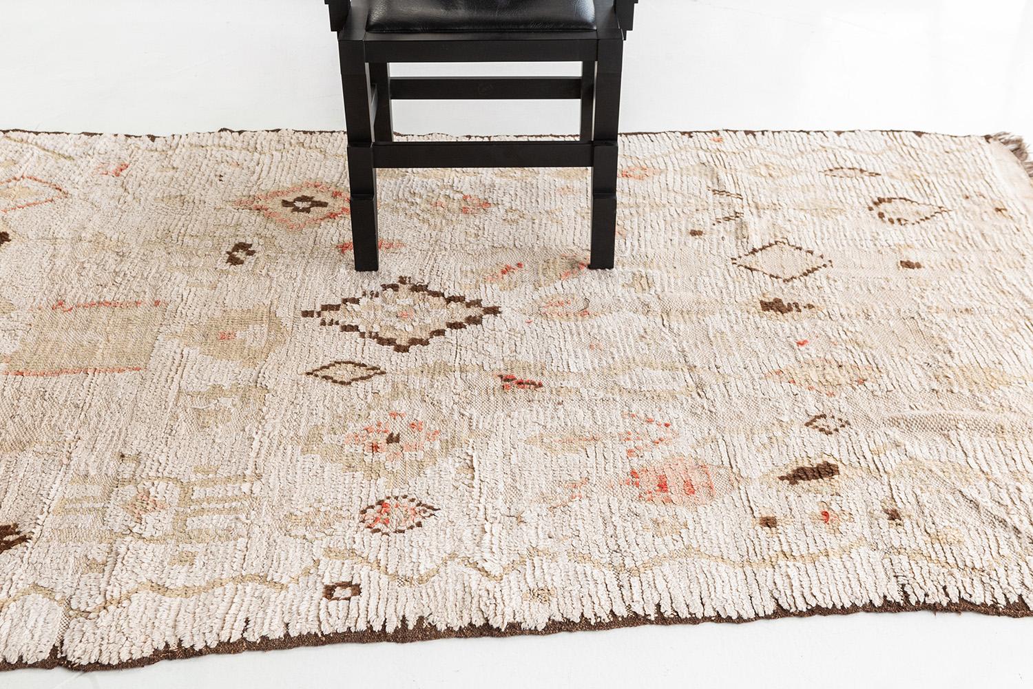 A simple yet elegant Azilal Tribe Moroccan rug from Atlas collection consists of various Berber motifs, hazel tones of zigzag, diamonds, crisscross in a glorious ivory field which makes the rug more unique. Perfect centerpiece for your office,