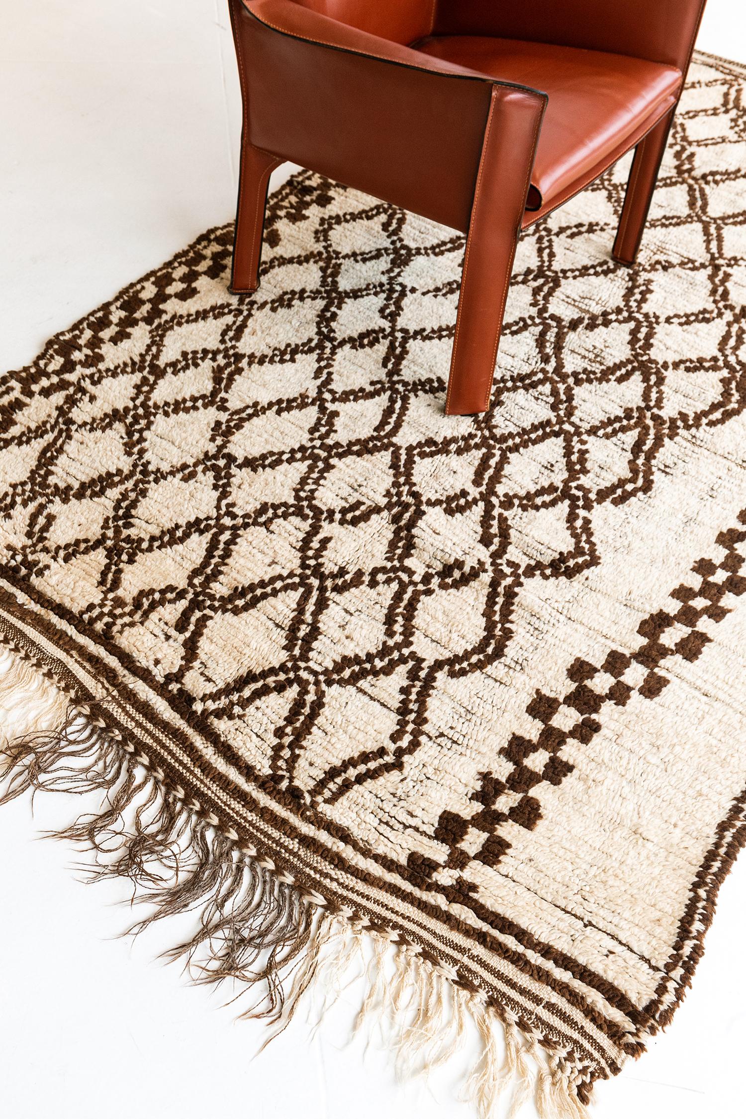 A fascinating vintage Moroccan rug of Azilal Tribe that appears to have a brilliant graphic combination of X shapes that eventually transformed into an all-over pattern of lozenge trellis and enclosed by a series of partridge eyes on both sides.