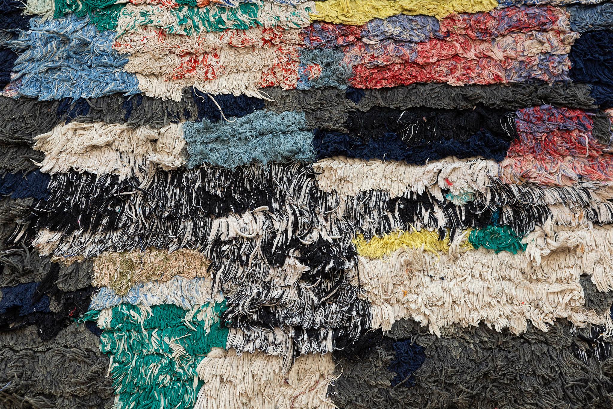 Un tappeto marocchino vintage della Tribe Rugs, caratterizzato da blu freddo, corallo, marina, grigi, avorio e altri sporadici accenti colorati. I mucchietti colorati creano forme irregolari per una bellezza astratta. Questo tappeto è un esemplare
