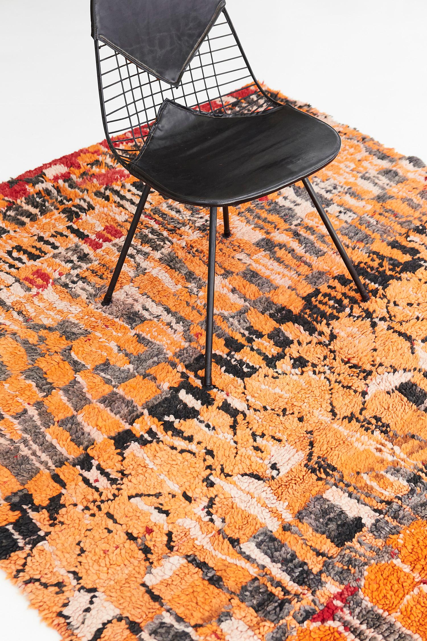 This magnificent rug has asymmetrical elements forming a pattern that perfectly resembles modern cubism. The featured shades of tangerine, charcoal, and ivory in this vintage rug complement each other and allow the well-defined elements to create