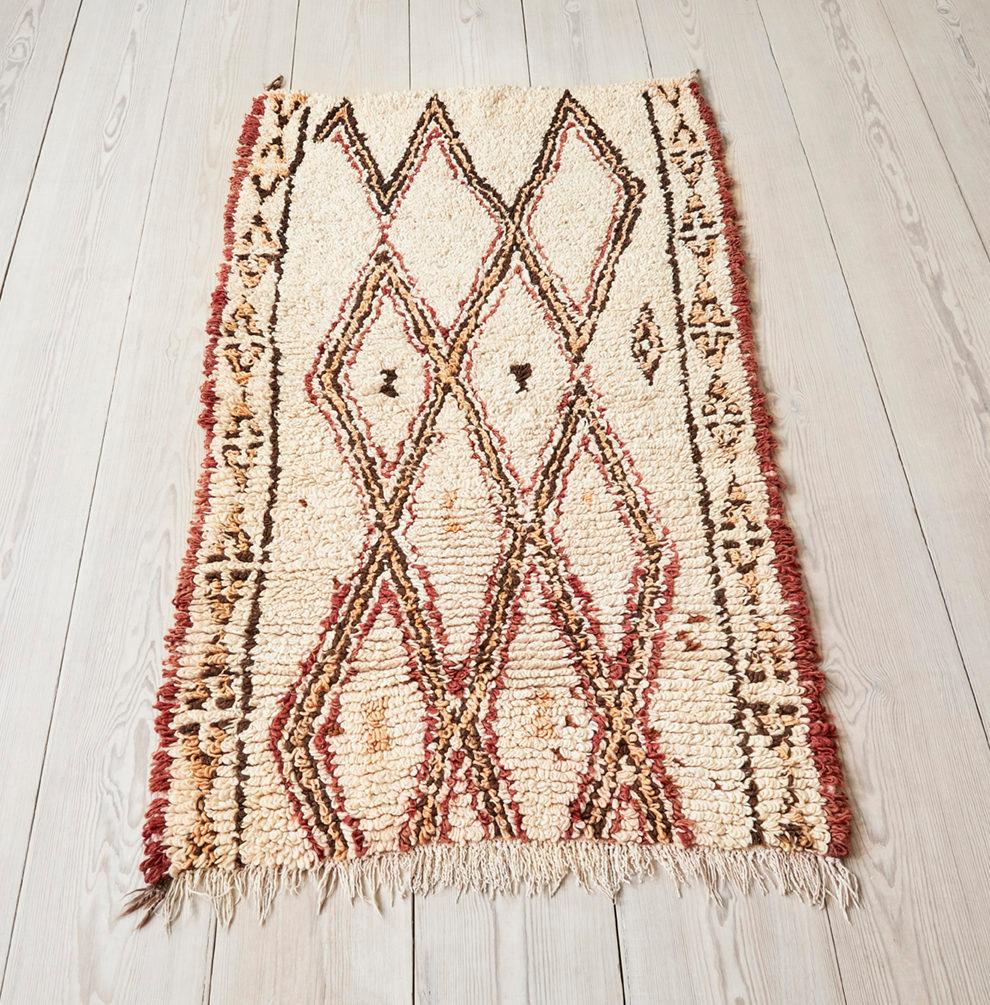 White Beni Ouarain pile rug with a red, brown and yellow pattern.