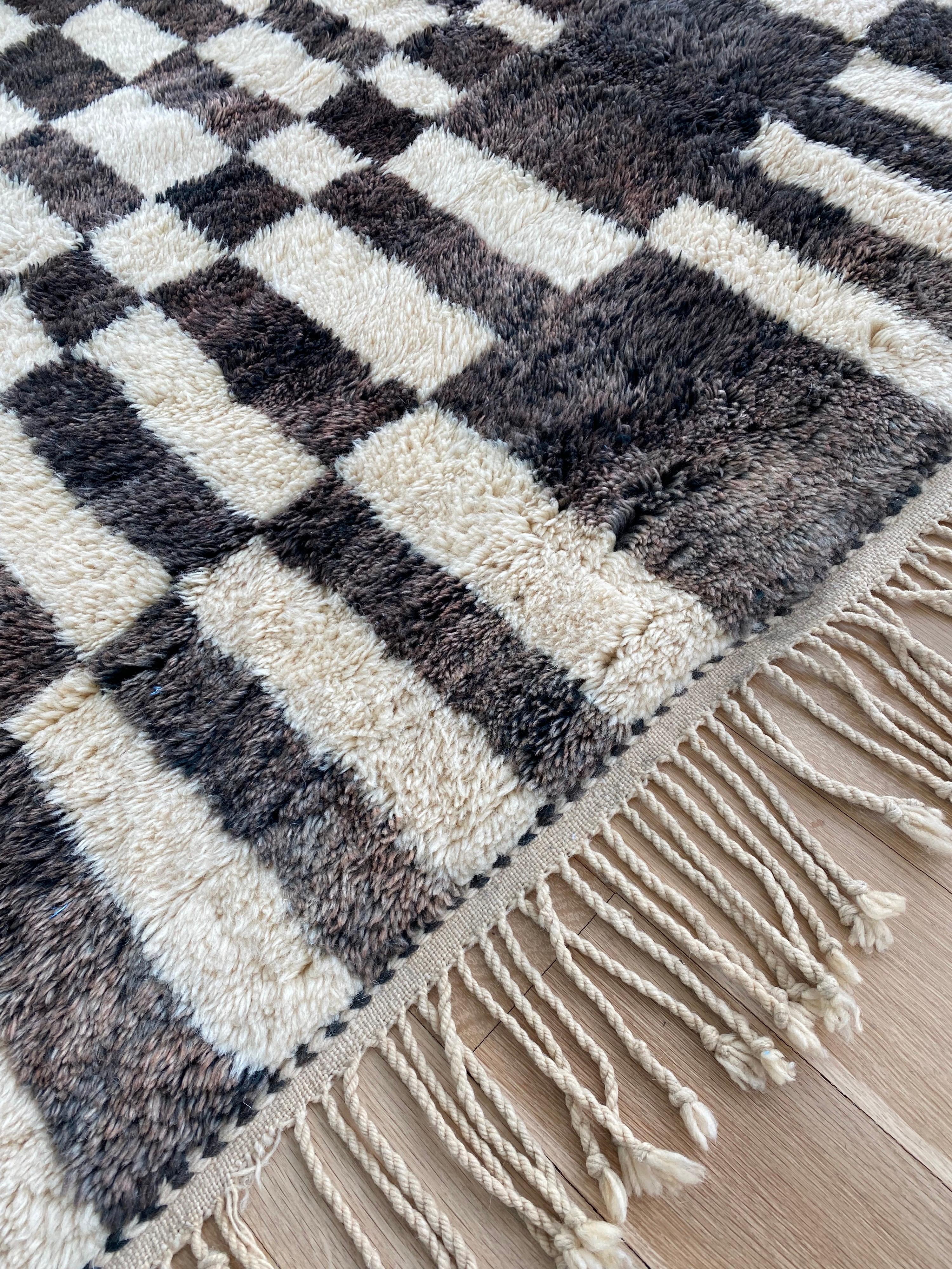 Un tapis marocain vintage Beni Ourain avec un motif en damier intéressant et inhabituel. Merveilleuse couleur noire/chocolat et crème. Les pilotis sont en excellent état et doux au toucher. Les glands d'origine sont intacts avec une tresse tissée à