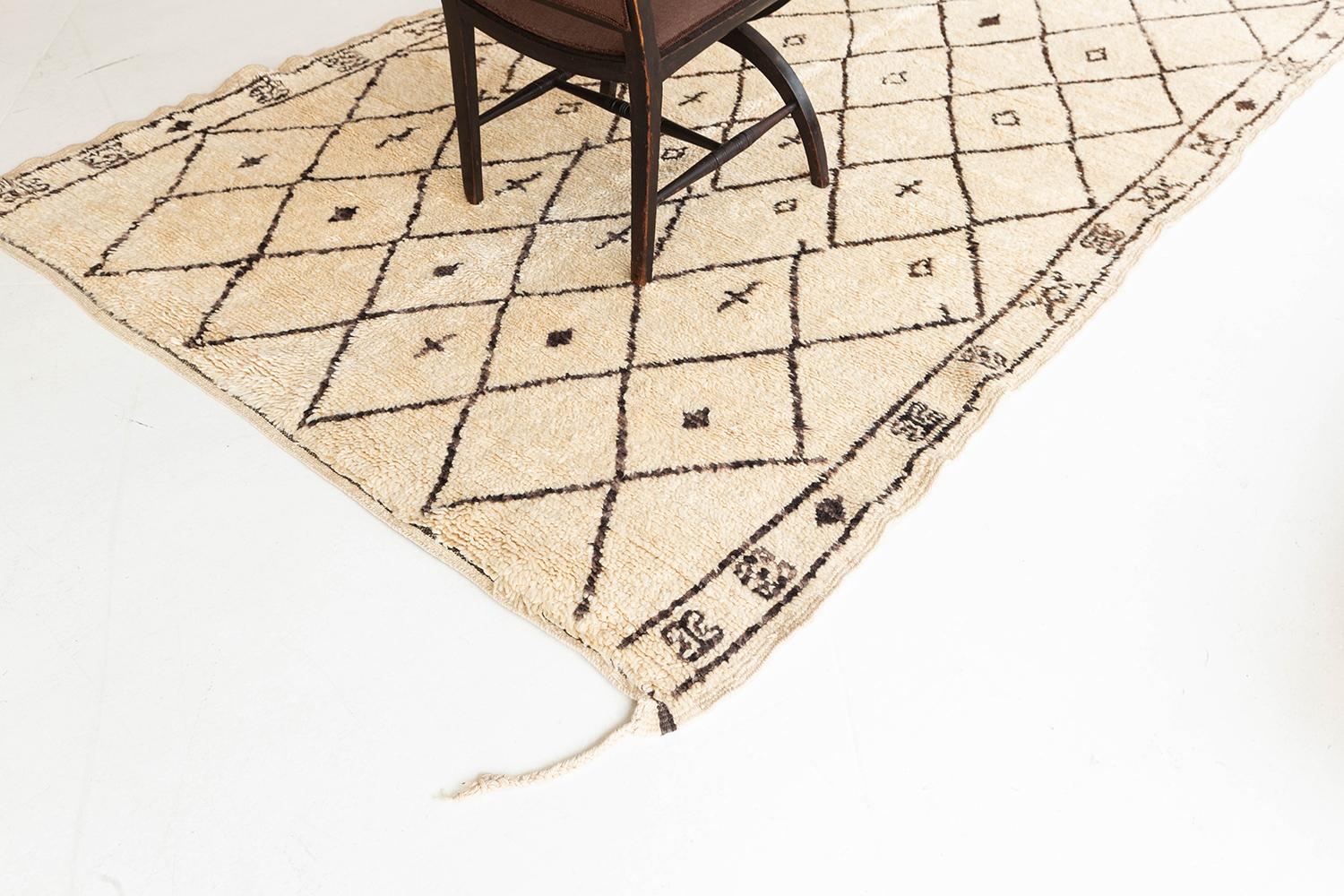 A beautiful antique Moroccan rug made by the Beni Ourain Tribe. This unique handwoven rug contains traditional diamond line-work with symbolic motifs throughout including the rug's borders. Beni Ourain tribal rugs are known for their soft black or