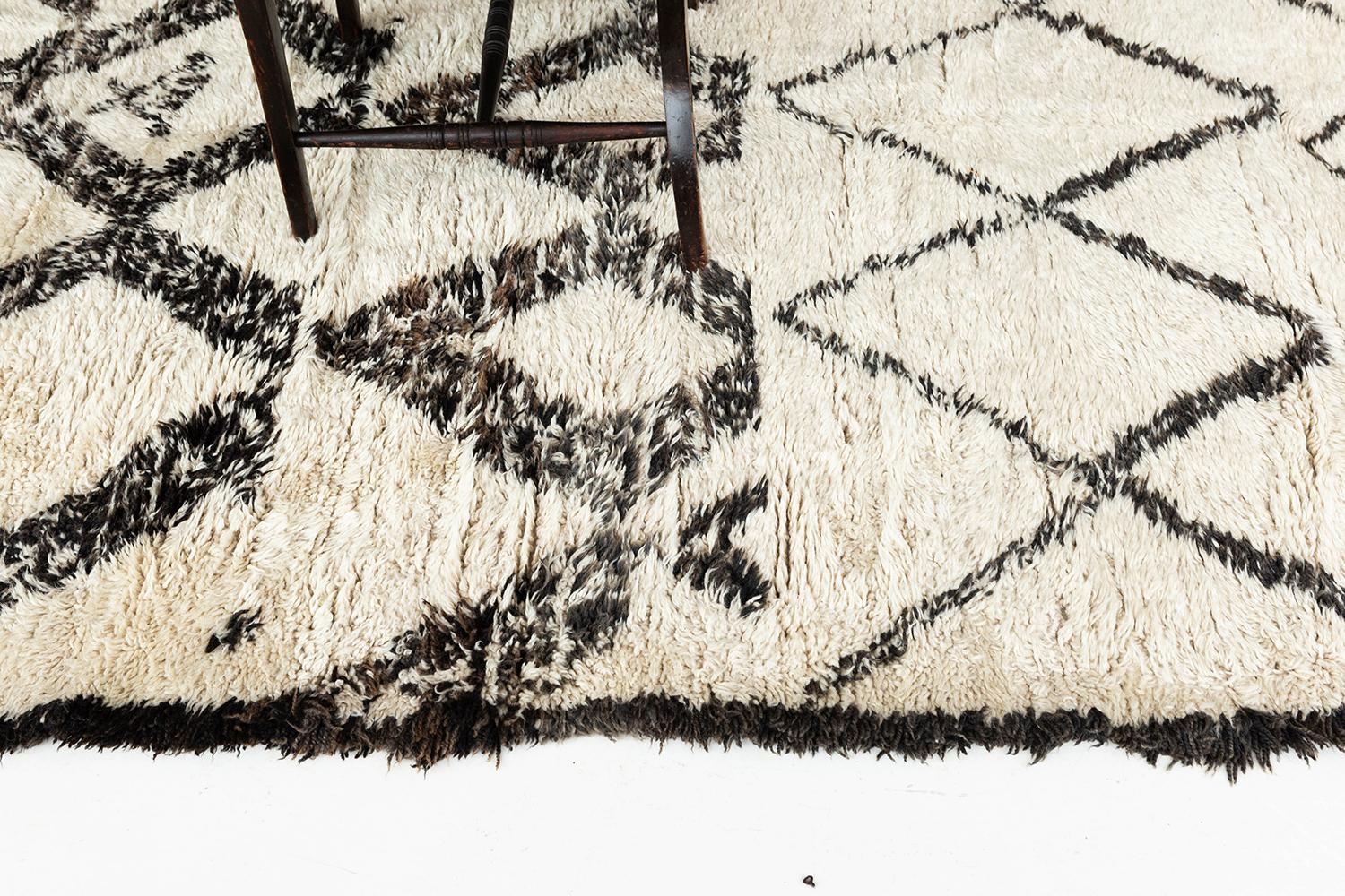 A beautiful antique Moroccan rug made by the Beni Ourain Tribe. This unique hand woven piece contains traditional diamond linework with symbolic motifs throughout including the rug's borders. Beni Ourain tribal rugs are known for their soft black or