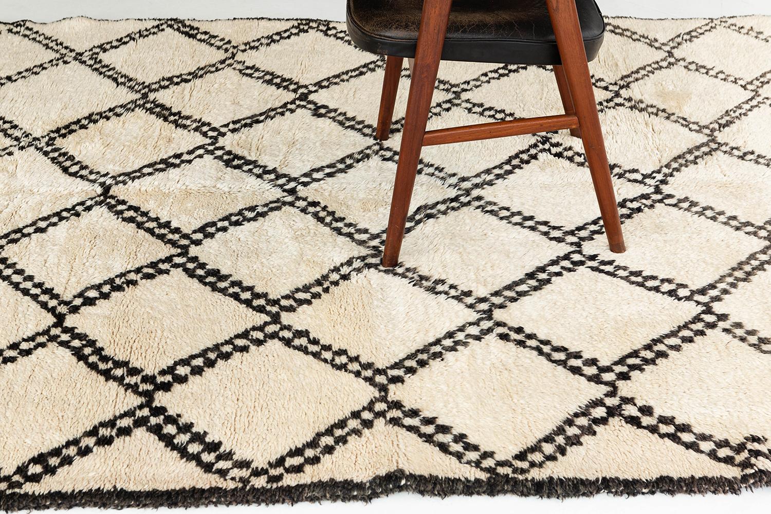 Ivory pile field with diamond lattice pattern rendered in alternating dark brown and ivory with rows of embellishments at the bottom of the rug. This is a unique vintage rug from the Beni Ourain peoples of Morocco.