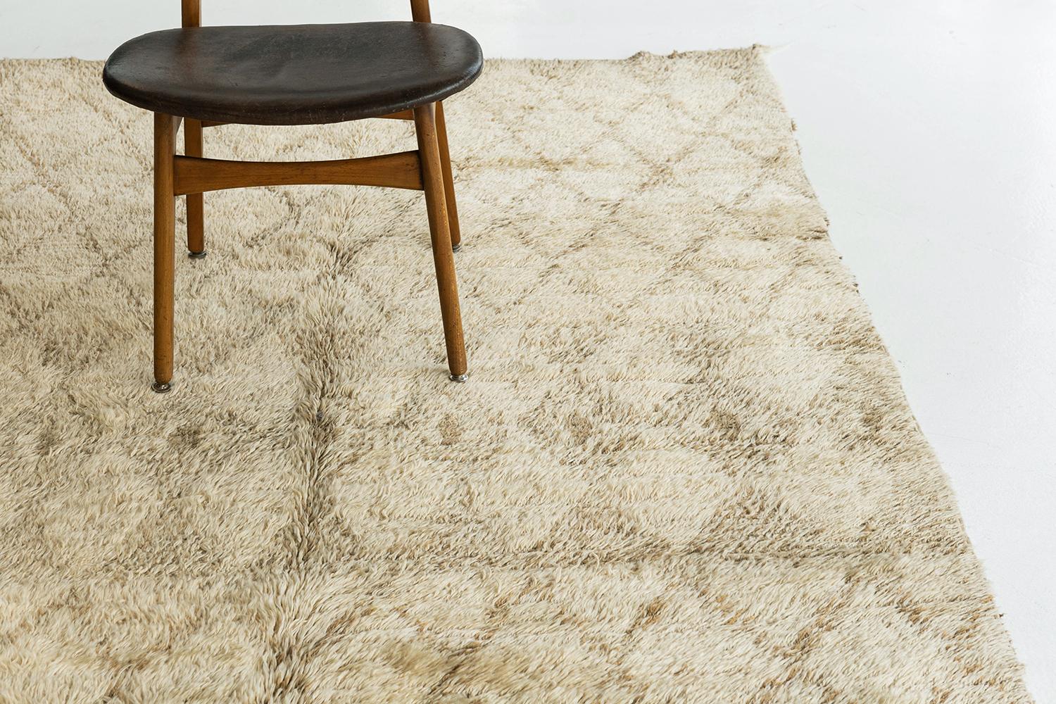A beautiful vintage Moroccan from the Beni Ourain tribe. This charming handwoven wool piece has the perfect sandy ivory color and contains traditional diamond motifs latticed throughout the field in a golden hue. A one of a kind rug that will leave