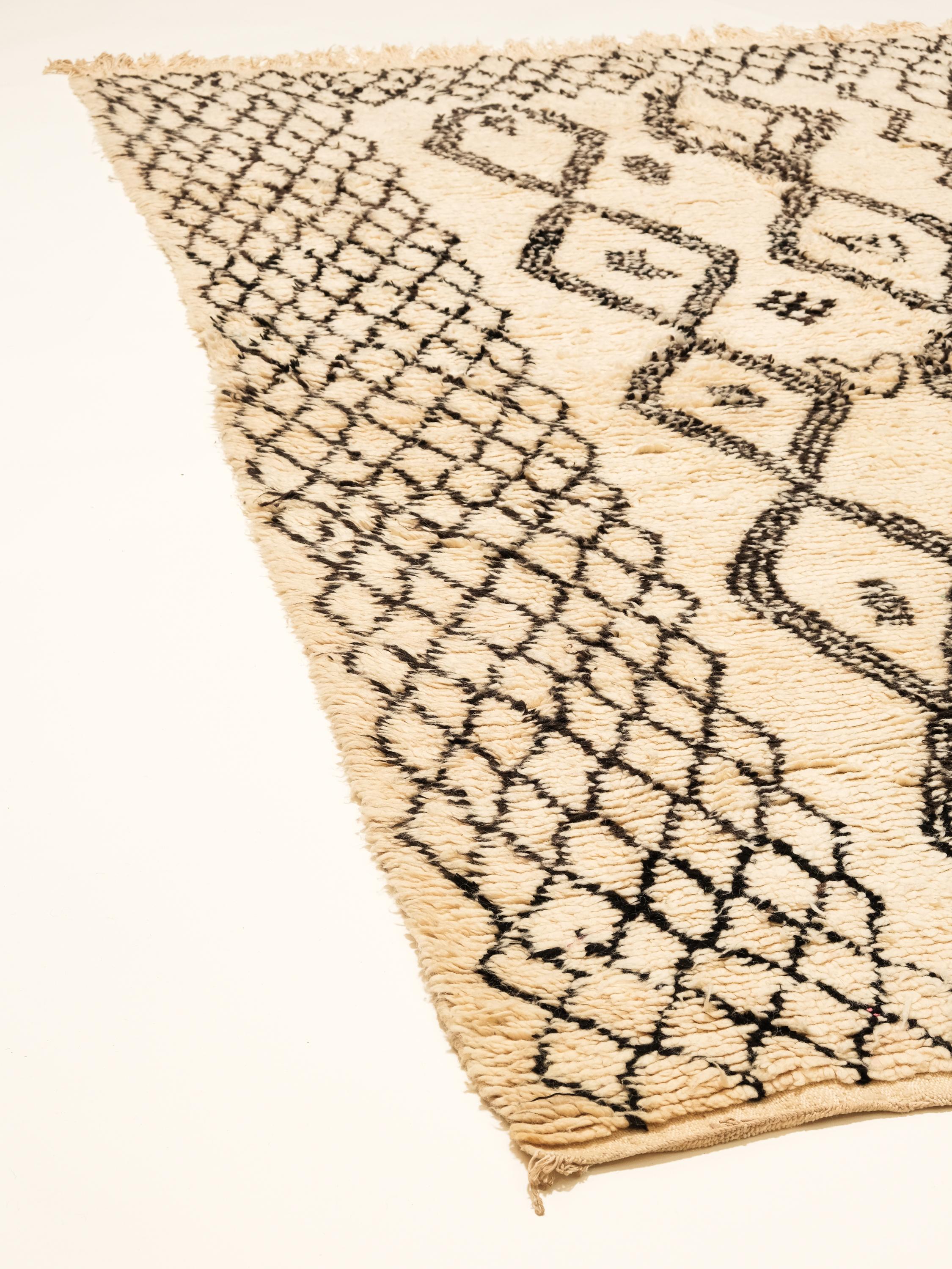 A beautiful vintage Moroccan rug from the Beni Ourain tribe. This charming handwoven wool piece has the perfect sandy ivory color and contains traditional diamond motifs latticed throughout the field in a golden hue. A one of a kind rug that will
