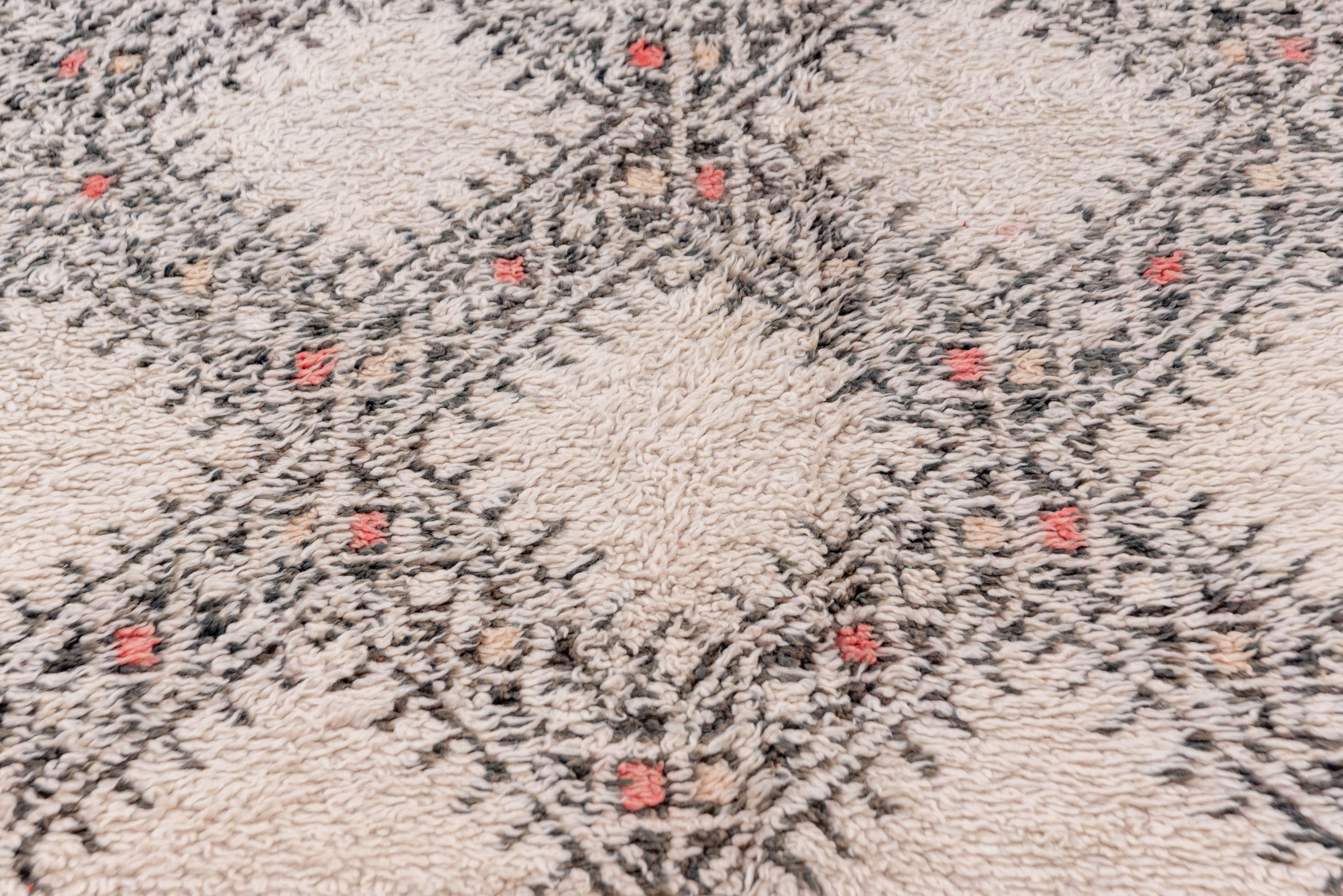 This long pile, two-tone carpet was woven by a Berber tribe in the Atlas Mountains of Morocco. The brown and ivory colors are undyed, directly from the nomads' own sheep. The rayed, open lozenge pattern is framed by an undecorated open square