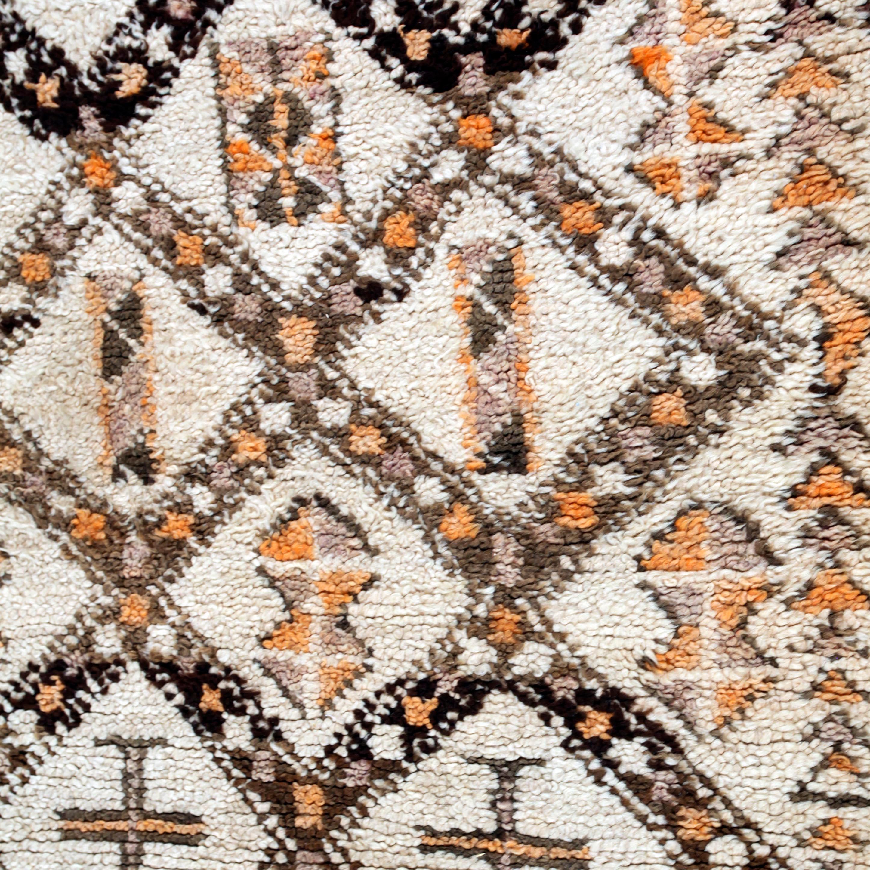 A wonderful array of subtle browns, with accents of faded purple and henna orange on a natural field of wool. Berber tribes produce some of the finest quality rugs in all of Morocco. These rugs show an archaic symbolism that dates back to the