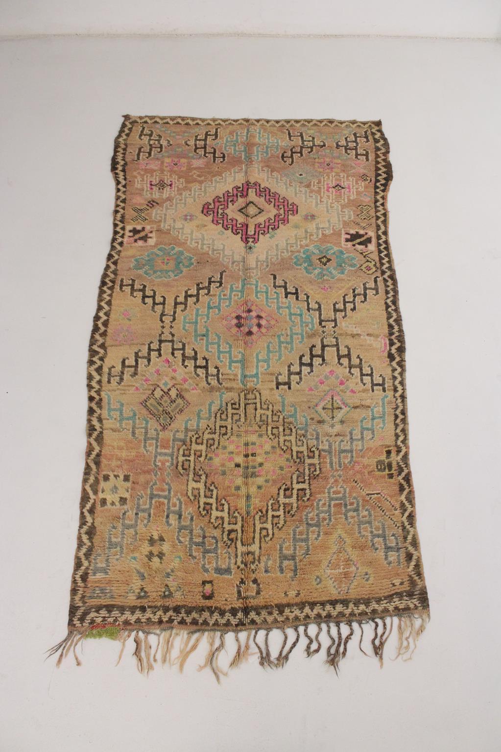 I selected that Boujad rug from piles of carpets because I think that it's a lovely piece with such sweet colors! I would call the main background color a dusty peach, with black, pink, cream and turquoise designs like a repeted, traditional hooked