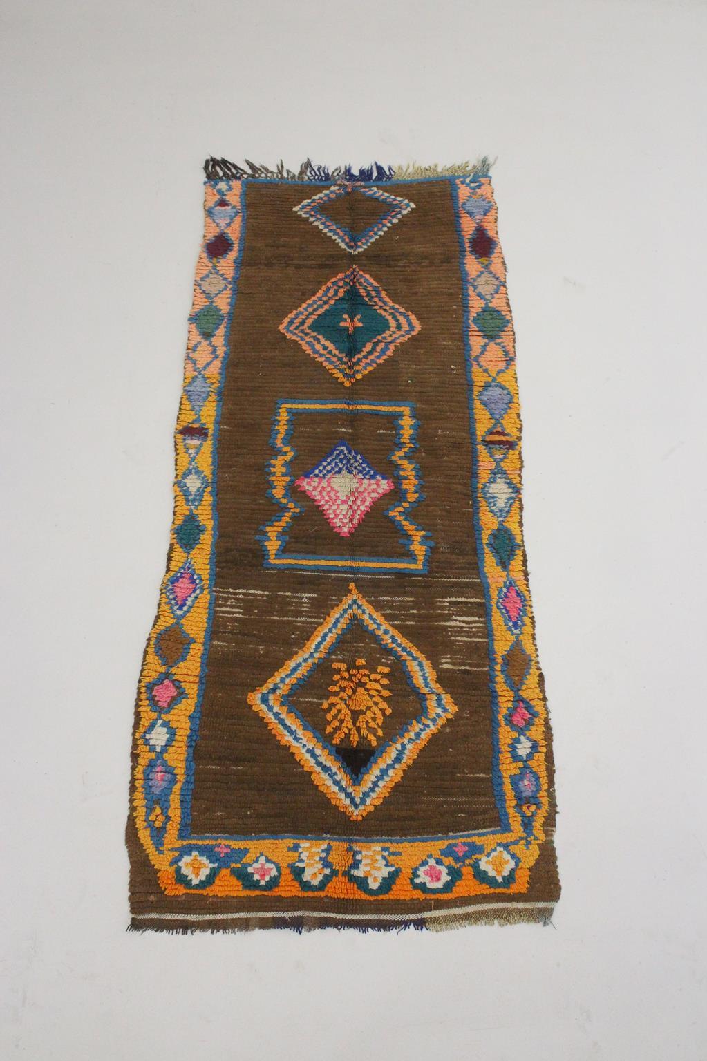 This vintage runner rug will bring the perfect bohemian vibe to your space! Probably made in the area of Boujad, Middle Atlas, Morocco, the rug features four bold designs, mostly diamonds, in blue, pink, yellow and white, on a coffee brown