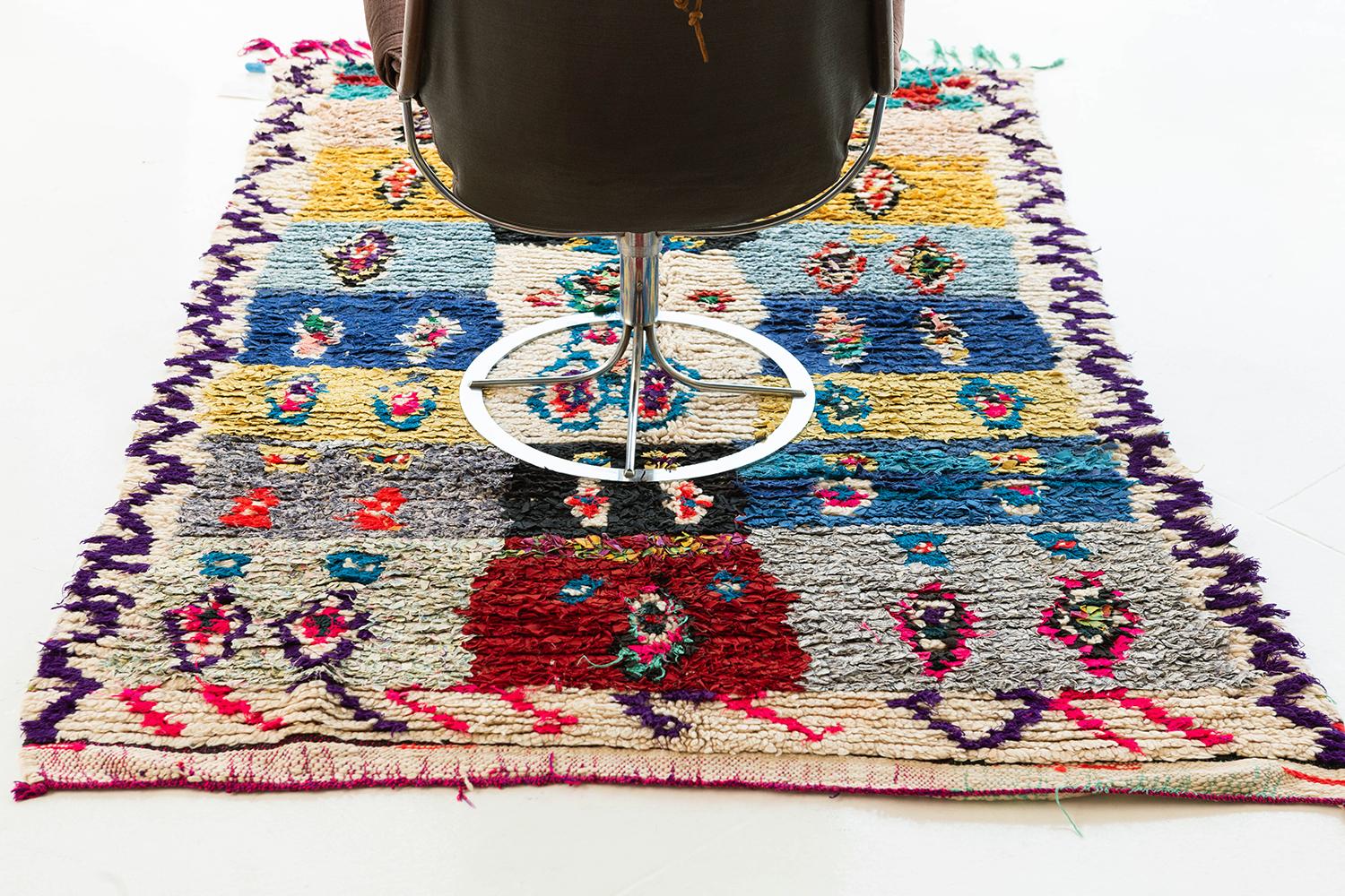 Playfully vivid ribbon-rug of rectangular compartments with interior medallion elements, and zigzag borders. Primary colors include ivory, yellow, blue, black, red and pink. Materials include recycled textiles and fibers-- a traditional practice