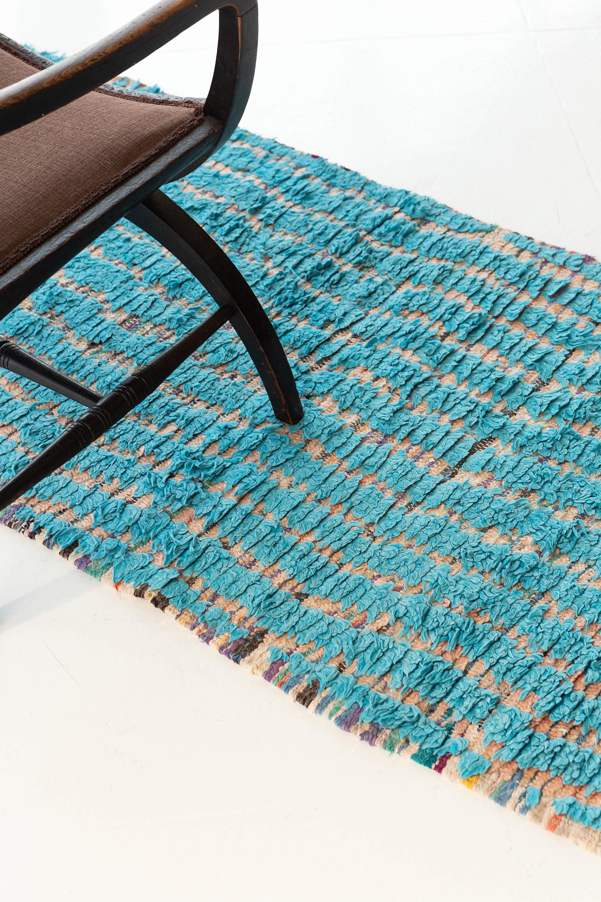 A compressed zigzag motif of alternating soft pink and brilliant light blue pile. Colorful variation in weft color introduces vivid horizontal line elements between the knots. This is a unique vintage piece from the Boujad region of Morocco.