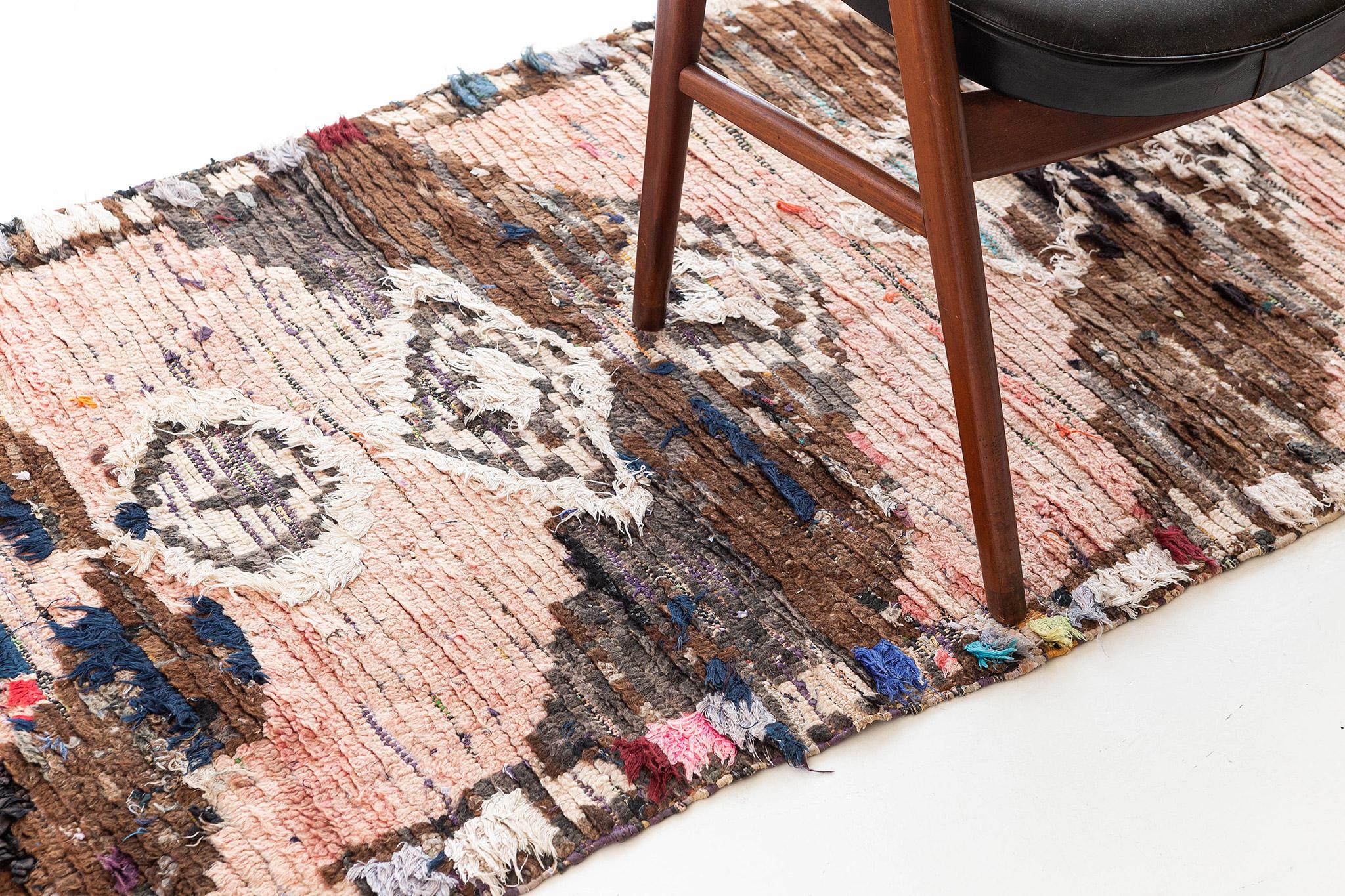 Alternating chevron stripes of rosy pinks and mottled brown run the width of the field. A column of irregular diamonds with nested contours in matching coloration runs through the center of the rug. Borders composed of stacked rectangles frame the