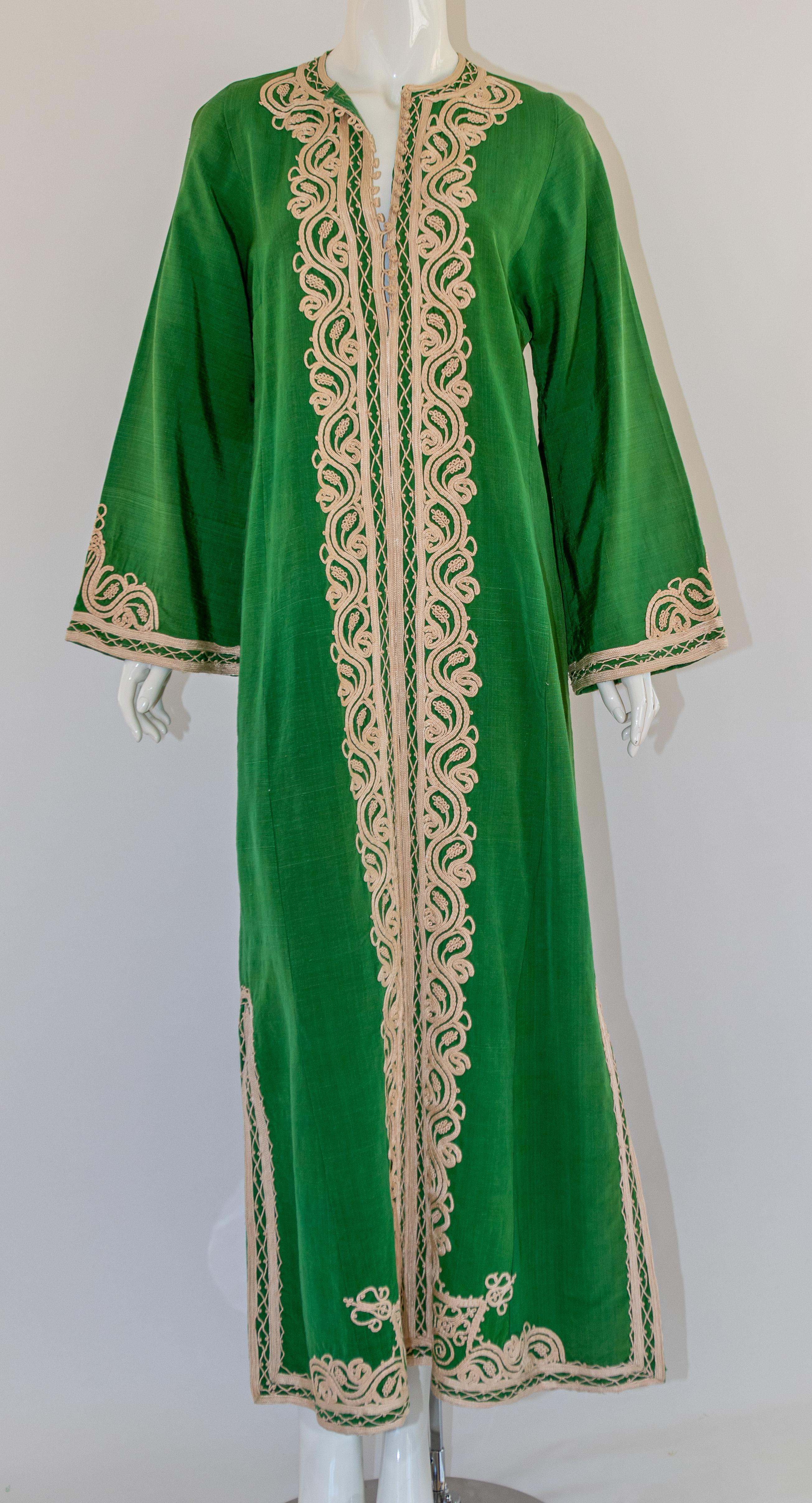 Élégant caftan marocain vintage en coton vert brodé d'un motif de fils blancs.  
Le kaftan présente un encolure traditionnelle, avec des fentes latérales fendues et des manches embellies légèrement cannelées. 
Elle se ferme à l'avant avec des
