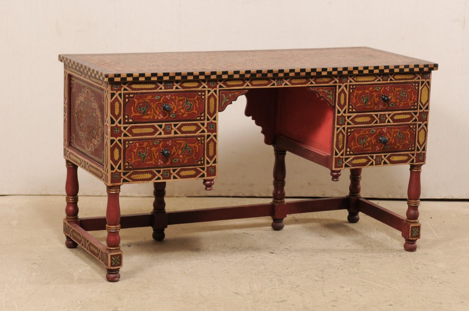 A vintage Moroccan desk with drawers which has been beautifully painted on all sides. This writing table from Morocco has been artfully hand painted in traditional Moroccan flare, with primary shades being of red and gold. The rectangular-shaped top