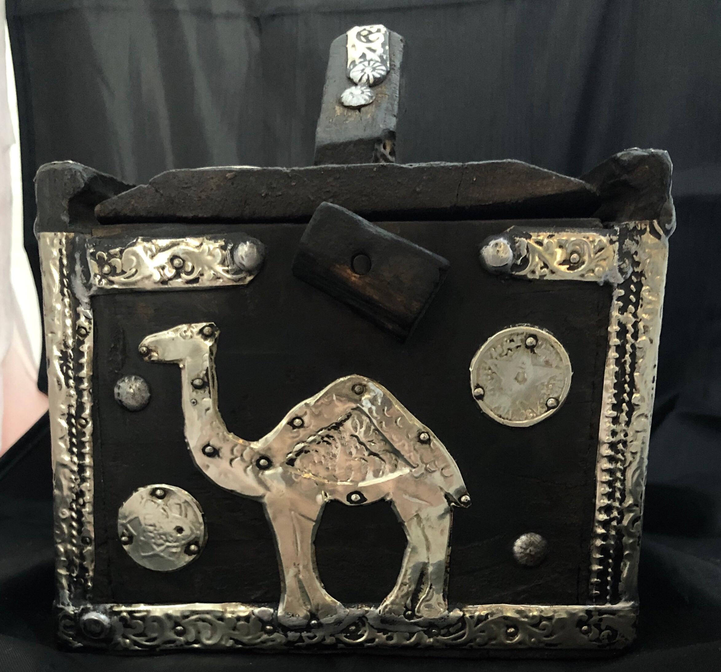 This eye-catching storage box was once used to store and transport eggs. Made in southern Morocco, the wood is sturdy tamarisk with silver and brass repousse and antique coins. 

The top of the box slides out, with a raised handle in the middle