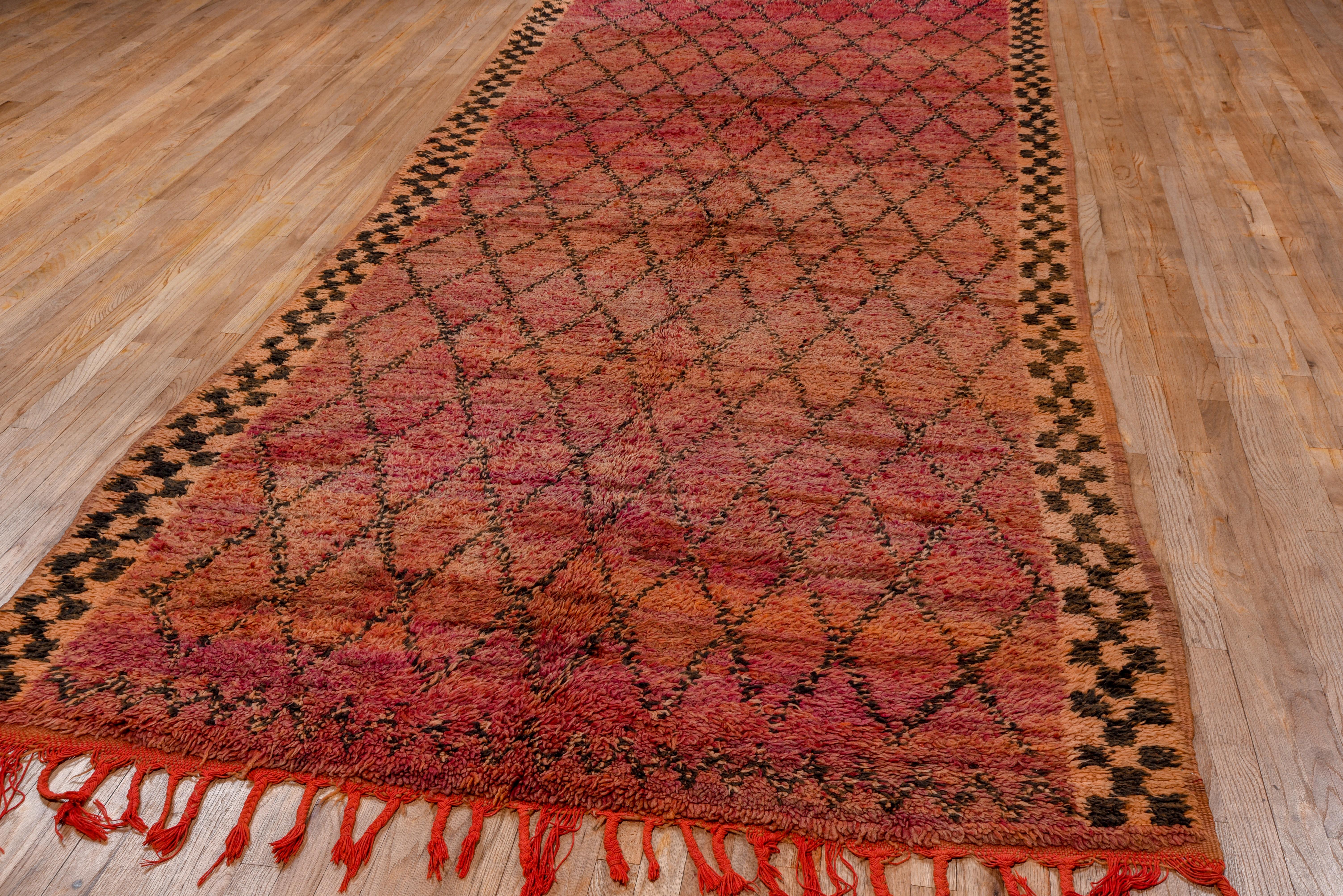 The orange side borders of conjoint position the abrashed raspberry field with a dashed brown open lozenge lattice pattern. Flat-woven pile-tone band at one end, tassels at the other. Good condition. Unusual palette.