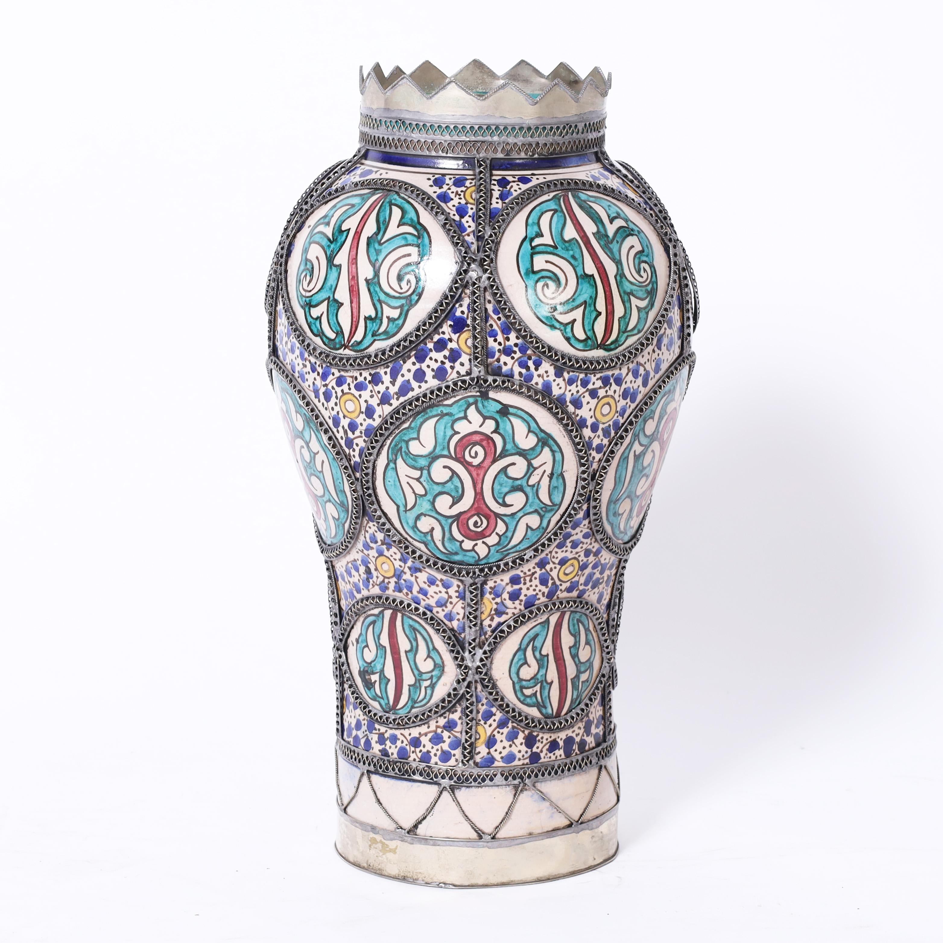 Standout Moroccan vase handcrafted in terracotta in classic form hand decorated on floral designs in distinctive Mediterranean colors under jewelry-like filigree metalwork.