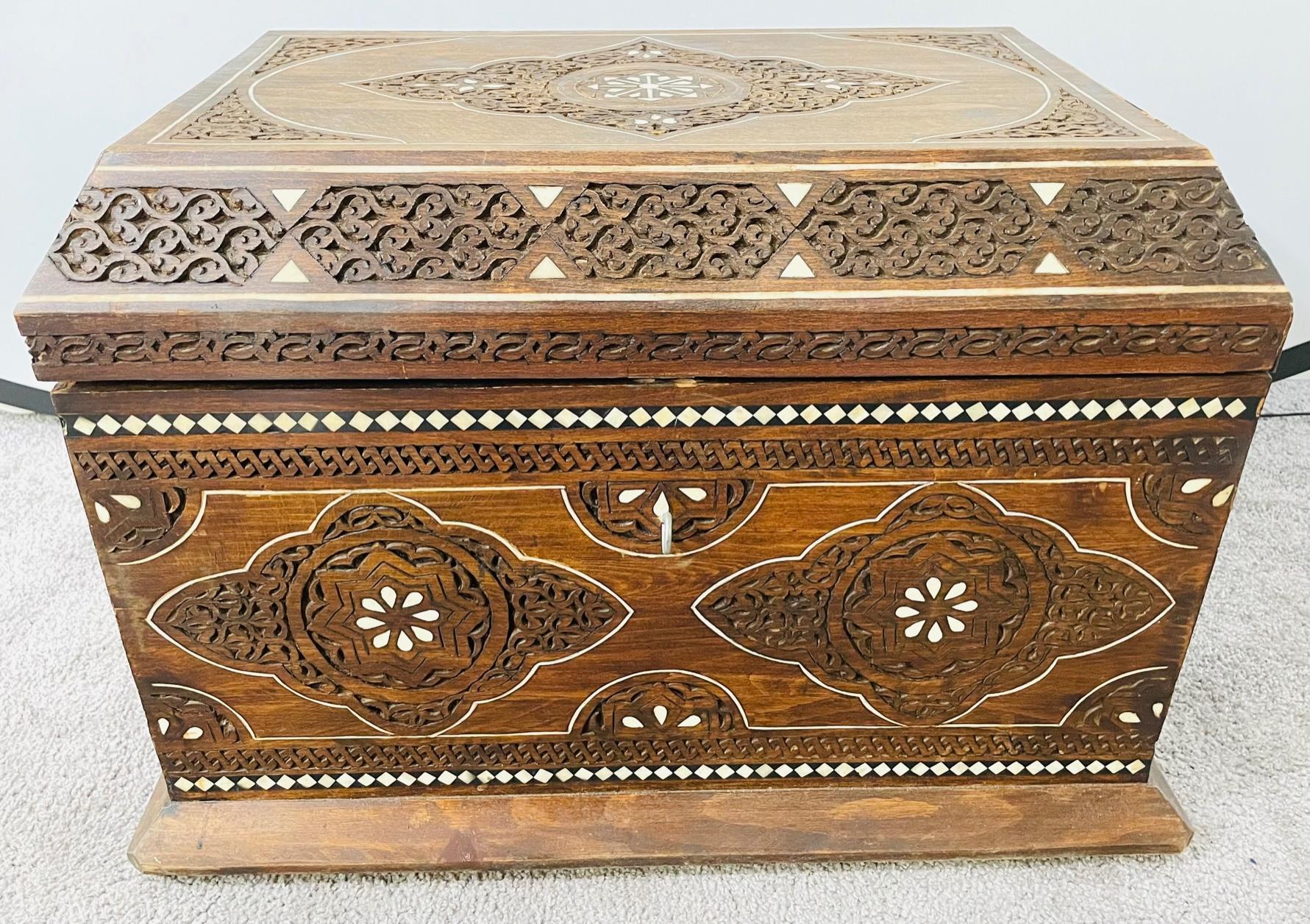 A 1950's beautiful one of a kind hand carved wooden Moroccan dowry chest. The chest features intricate moorish details and natural bone inlay. The interior is covered in fine genuine leather in a natural neutral color. Whether to store your valuable