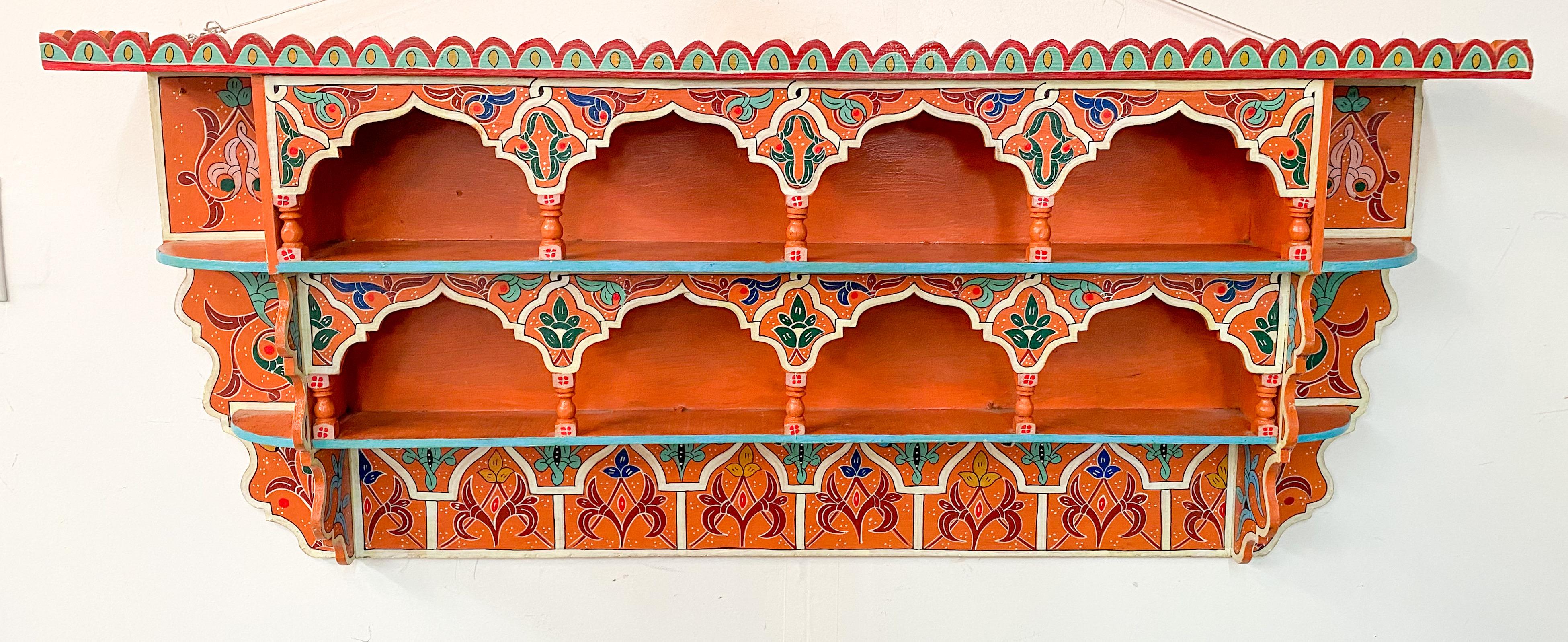 A beautiful vintage Moroccan Moorish wall shelf or spice rack. The Moroccan shelf is beautifully hand painted in vibrant orange with multi-color design and features centuries old Moorish design of geometrical patterns and arches with multiple