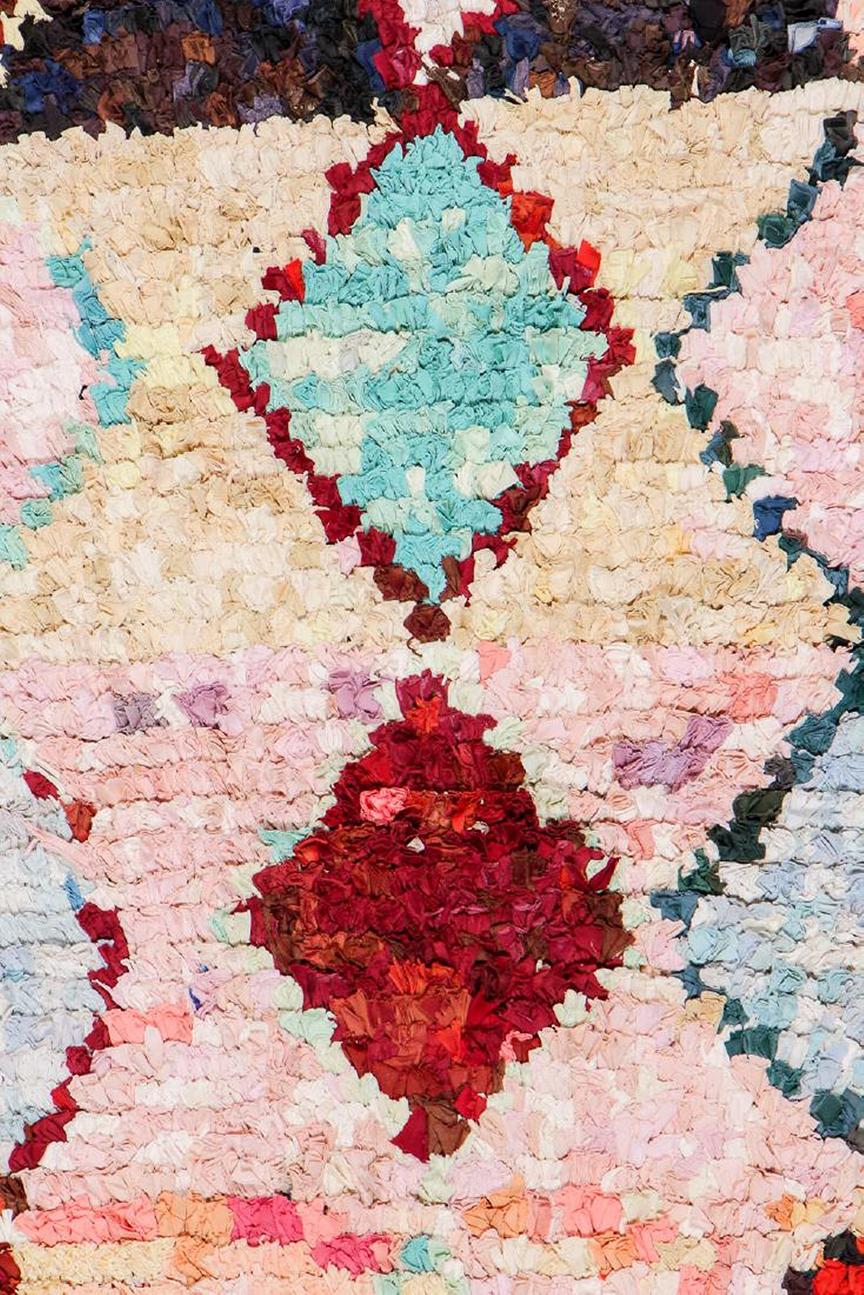 Annodato a mano in lana e proveniente dal Marocco verso il 1950-1970, questo pezzo vintage Boucherite di 3'5 x 7'10 della collezione Vintage Moroccan di Silk Road Rugs presenta una sensibilità testuale di buon gusto e una striatura multicolore su