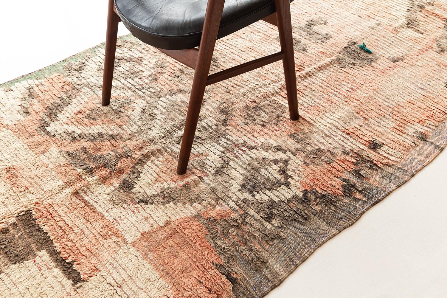 Un magnifique marocain vintage des tribus du Haut Atlas au Maroc. Les magnifiques couleurs taupe, rose, ivoire et corail du tapis créent un jeu de couleurs qui s'ajoute à la texture charmante et à l'imagerie symbolique du tapis. Cette pièce antique