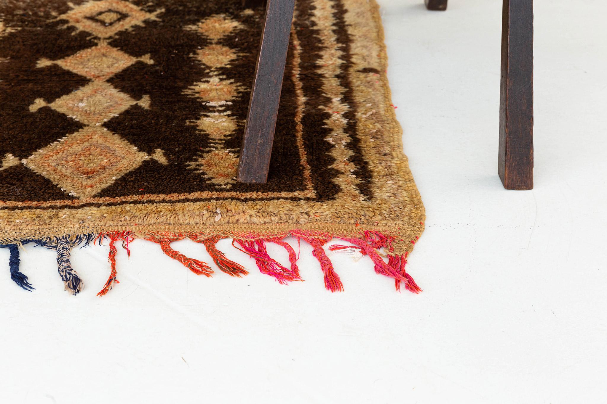 Small, near-square pile rug in warm tan and rich brown. An axial design of medallion column and parmakli diamond figures. Colorful warp structure yields a festive fringe. A unique vintage tribal rug from the Atlas Mountains of Morocco.

Rug
