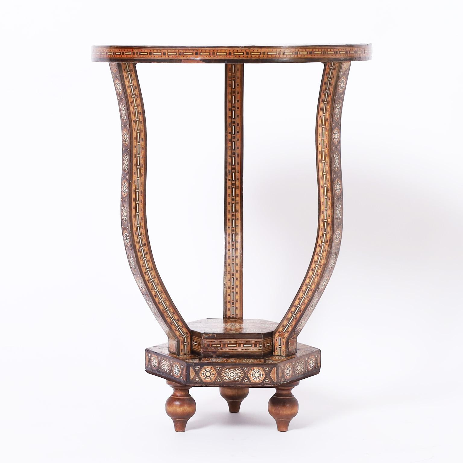 Impressive mid-century Moroccan stands having round tops decorated with inlaid marquetry crafted with mother of pearl and exotic hardwoods in star and geometric forms over three elegant inlaid legs on a double layered hexagon inlaid base with turned
