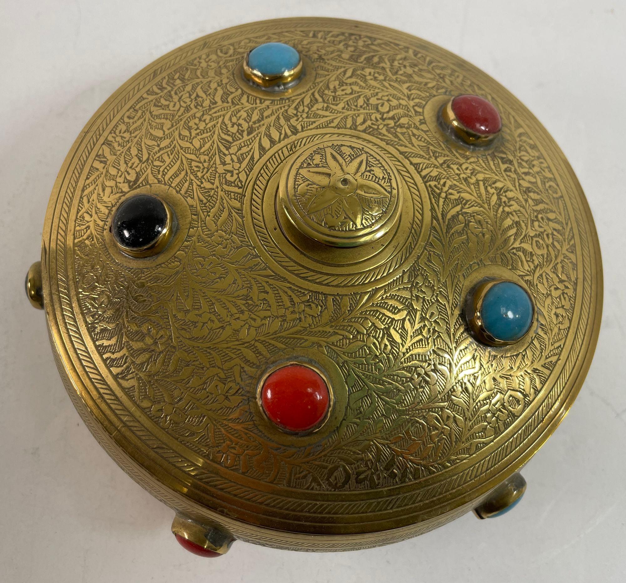 vintage Moroccan brass round trinket box decorated with multicolored jewelled beads in turquoise blue, ruby red, emerald green and onyx black.
handcrafted metal brass box with lid finely and delicately chased with floral and foliage design.
North