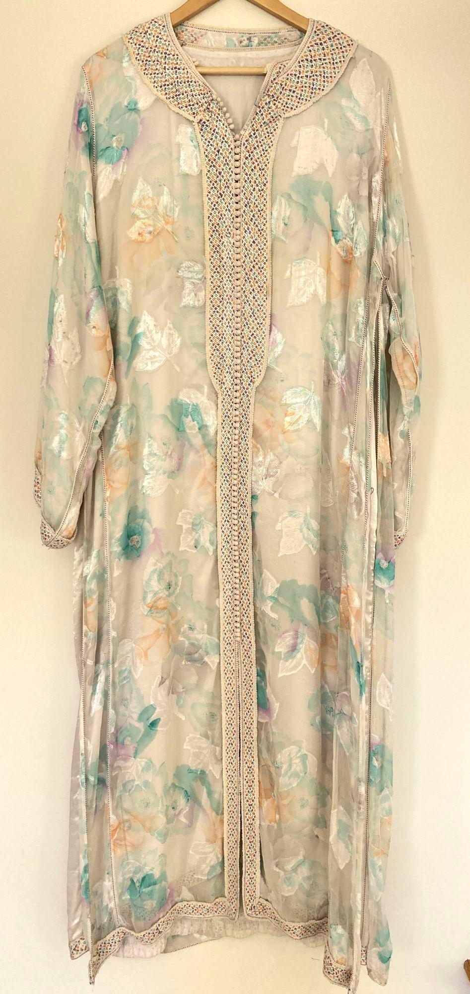 Elegant caftan marocain en tissu floral turquoise et or et garniture brodée à la main,
vers les années 1970.
Cette longue robe maxi kaftan est entièrement embellie à la main.
Il est confectionné au Maroc et conçu pour une coupe décontractée.
Robe de