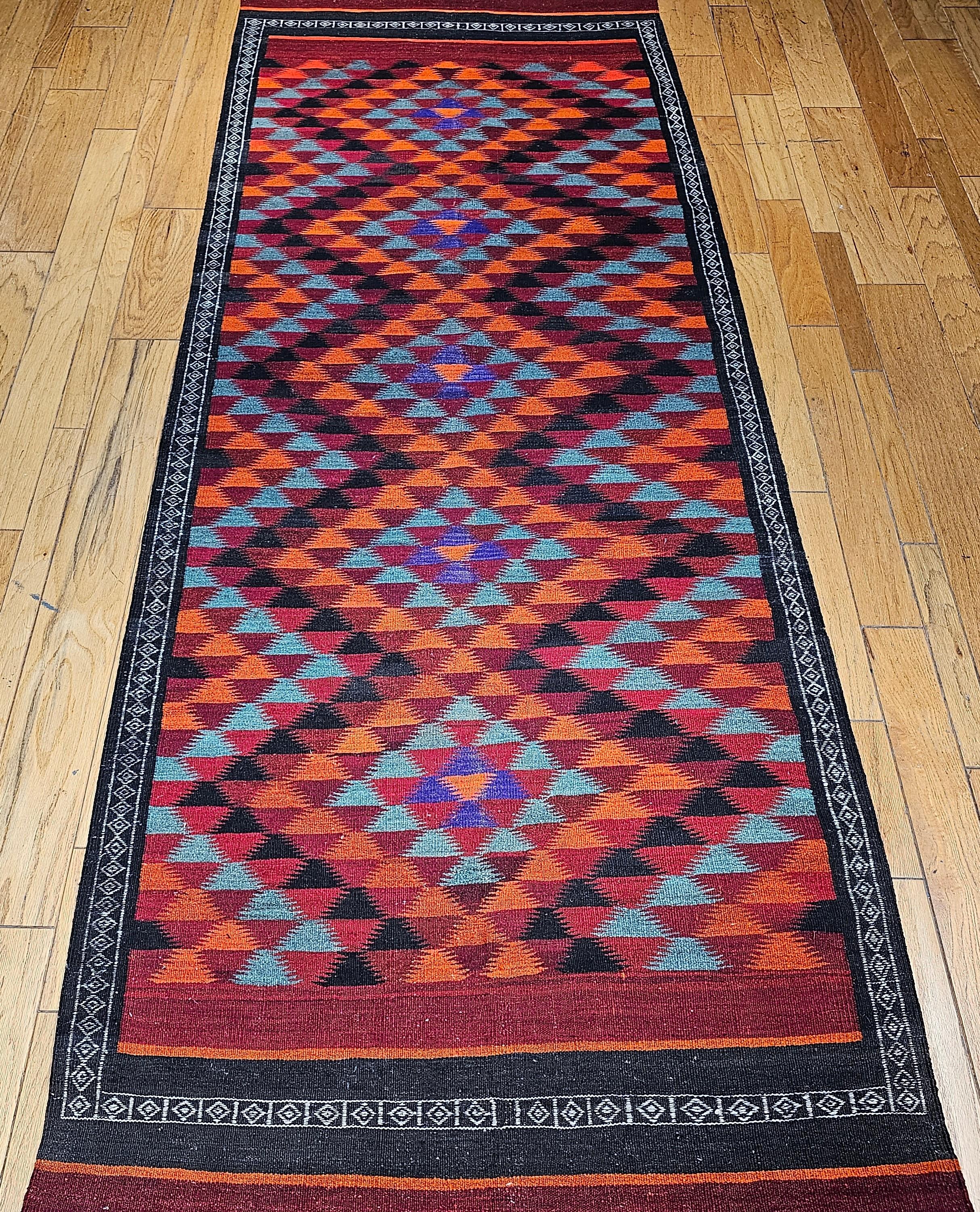 Preciosa alfombra de tejido plano o un kilim de mediados del siglo XIX.  La combinación de colores y el diseño recuerdan a las alfombras navajo del suroeste de EEUU.  Una serie de triángulos de color verde cerceta, rojo oscuro, morado azulado, negro