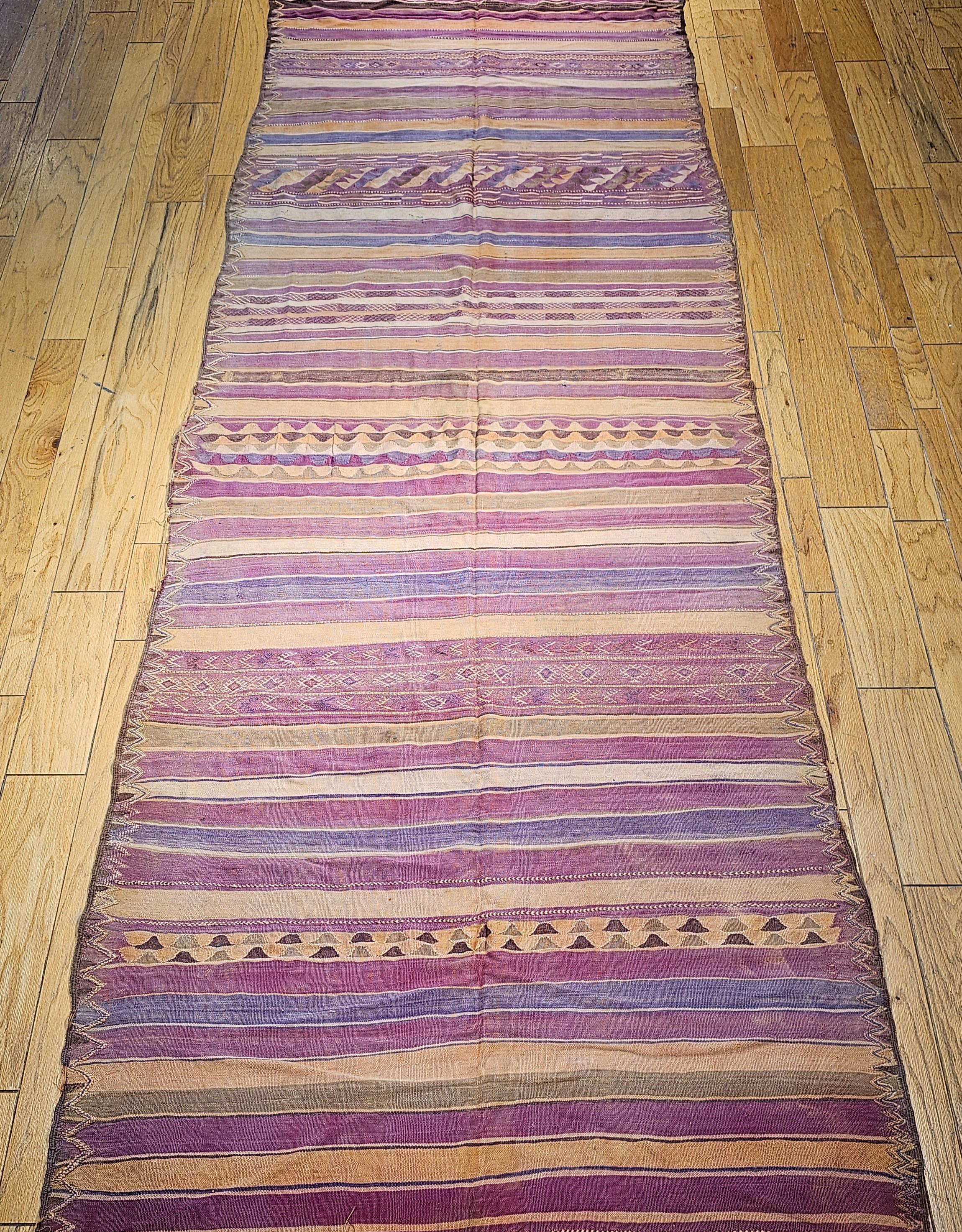 Vintage Moroccan kilim rug from the mid 1900s in a beautiful stripe pattern and wonderful soft colors in green, purple, yellow, brown, blue, and other shades.   The colors and the variations of them resemble the colors in an Arizona or New Mexico