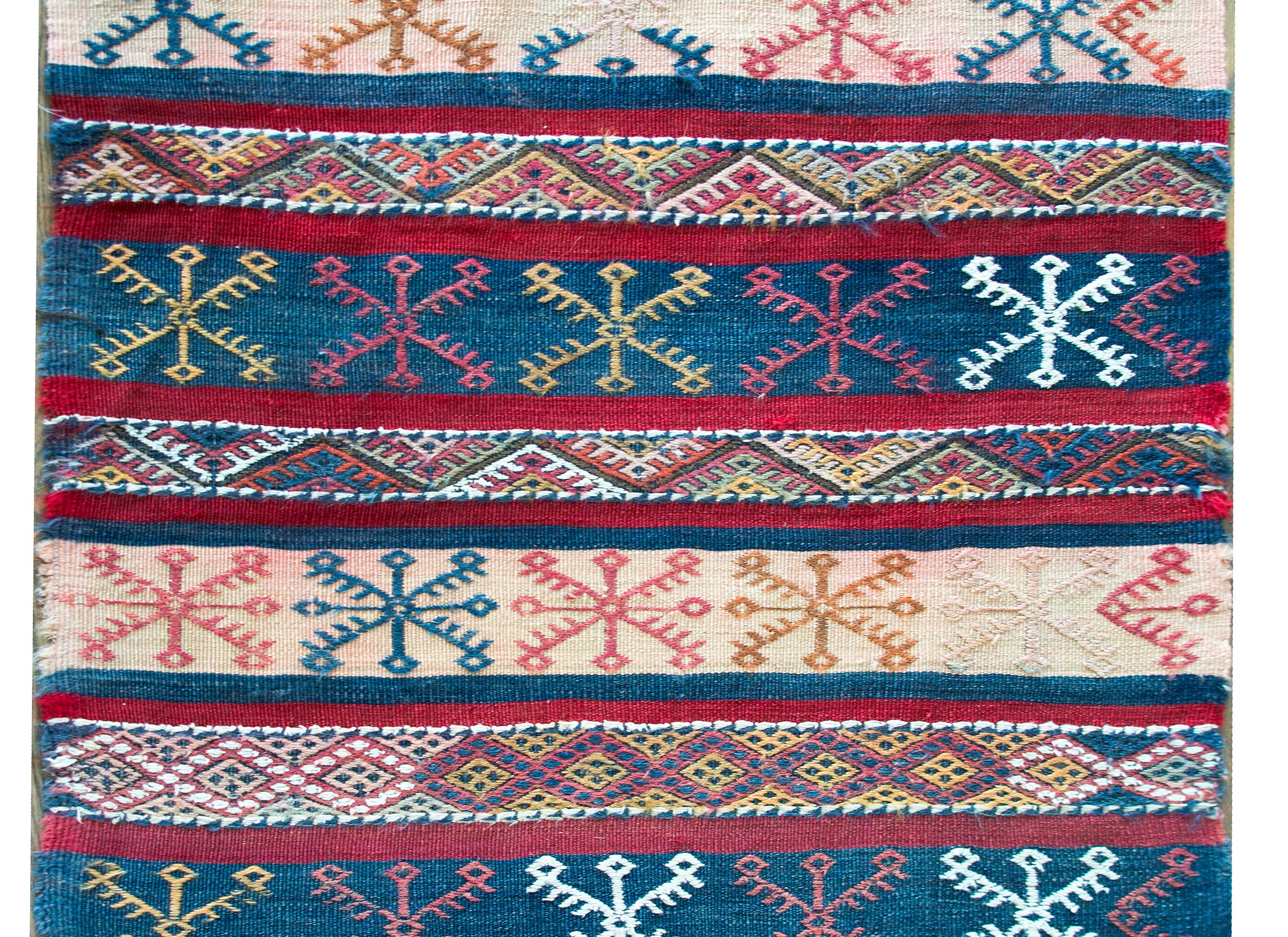 A chic vintage Moroccan kilim rug with a wonderful indigo, crimson, and cream striped pattern with embroidered stylized flowers across the entire rug.