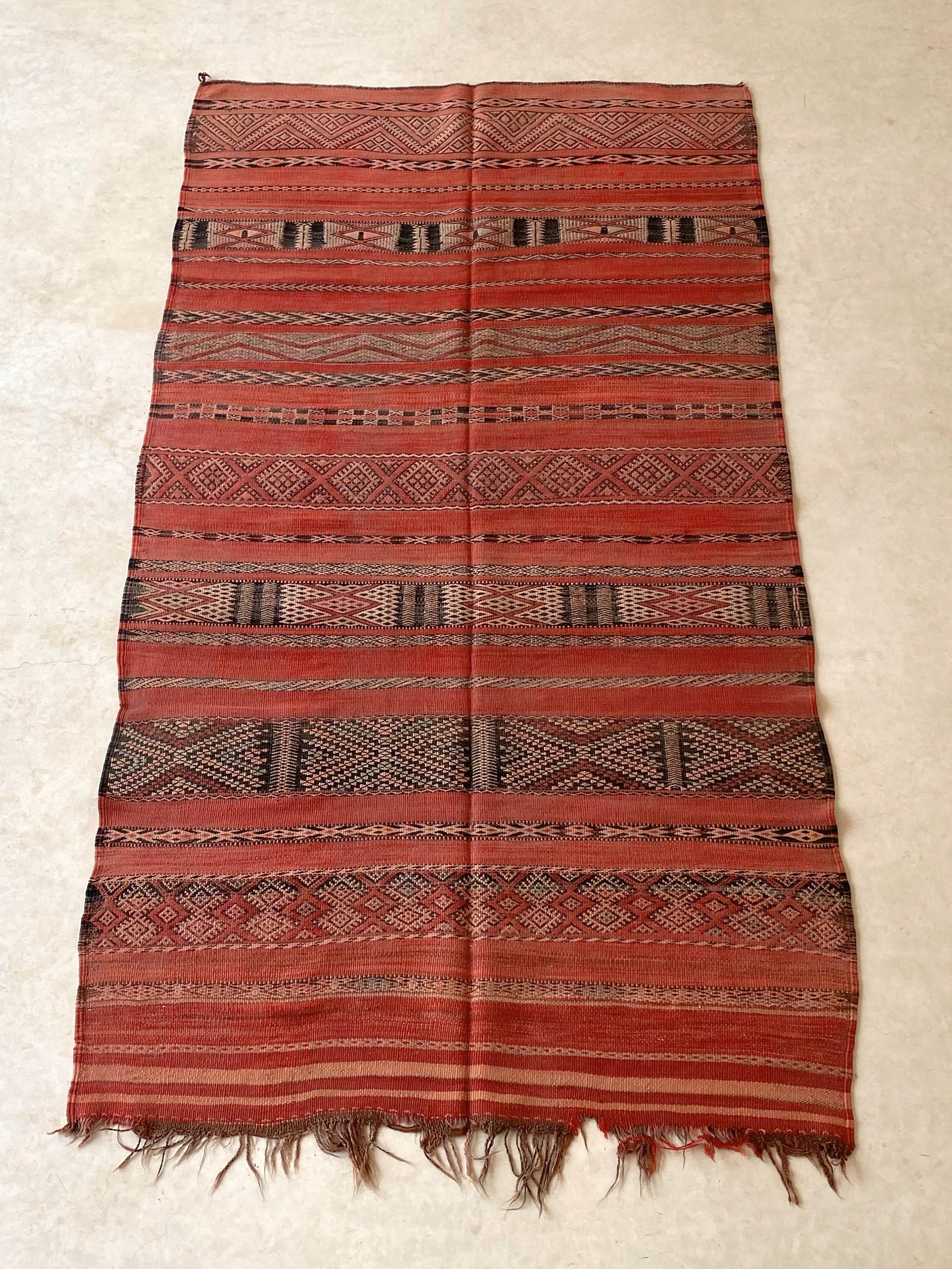 These vibrant, vintage kilim rugs with deep colors show such a strong character! This one here, probably from the Zemmour tribe, shows a classic pattern made of stripes with traditional embroideries. The main color is a red that shows several tones.