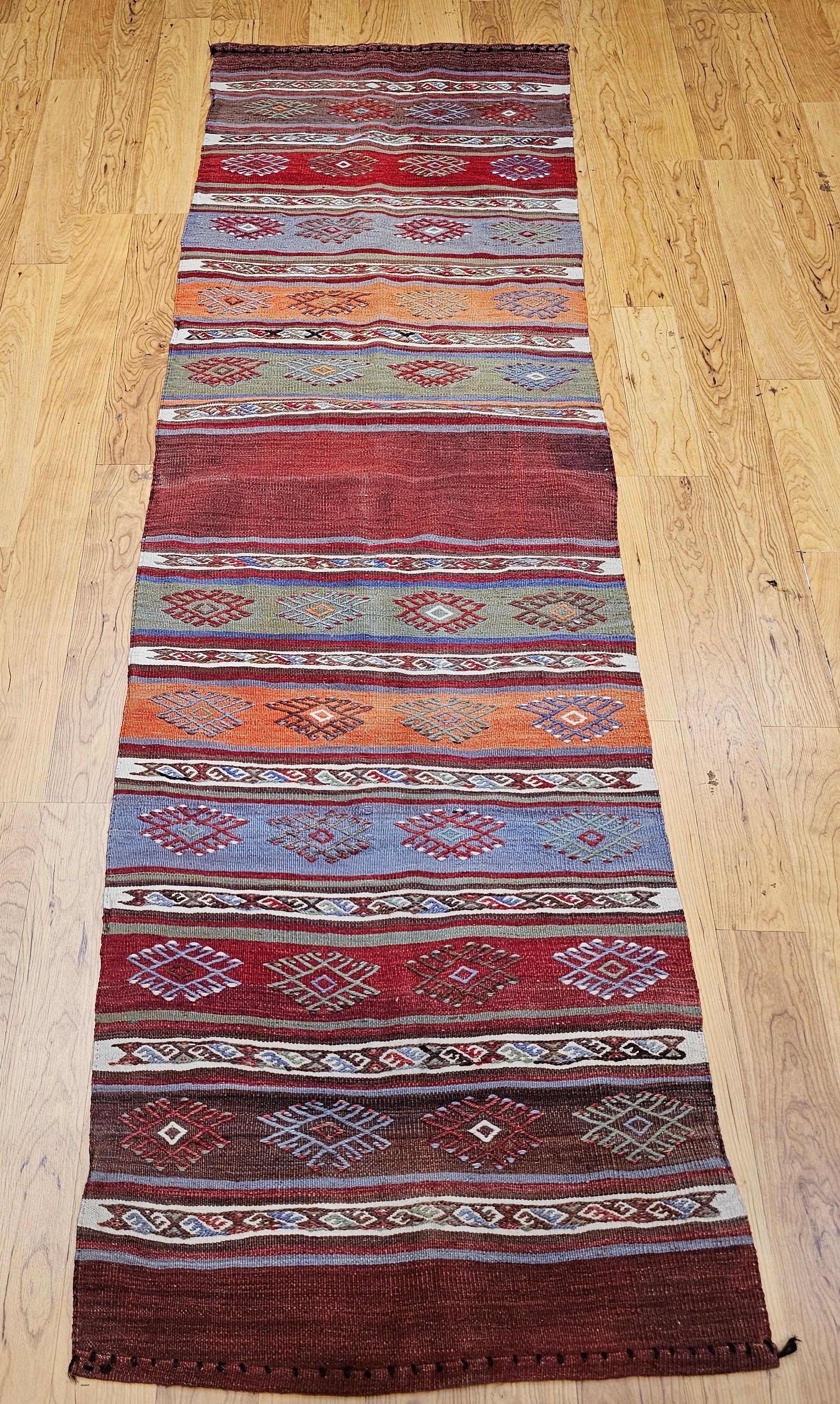 Discover the vibrant artistry and captivating spirit of North African weaving with this beautiful Mid-20th Century Vintage Moroccan Kilim Runner, handwoven circa the mid-1900s. This exceptional flat-woven textile features a dynamic stripes design