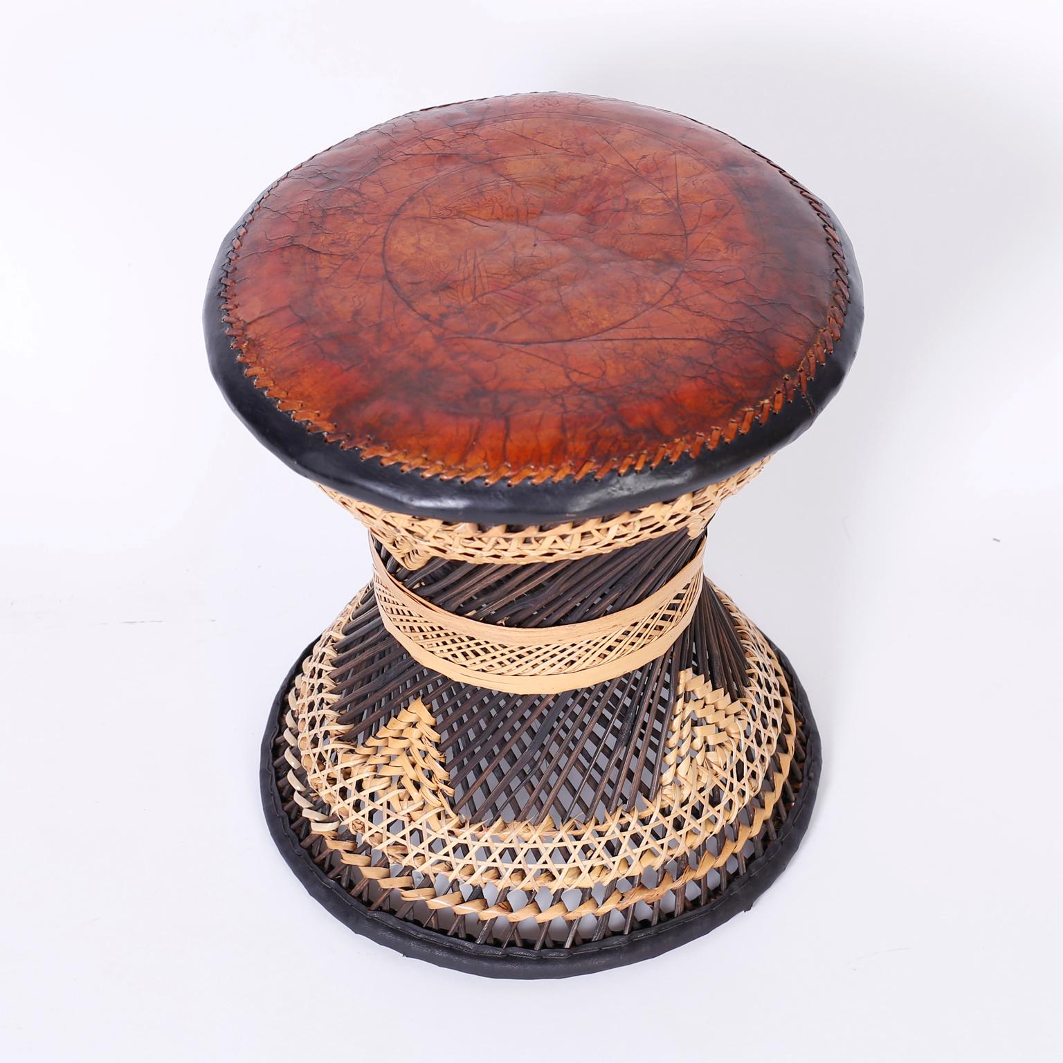 Midcentury stool with a rich brown leather top aged to perfection. The base is expertly crafted in stick wicker and decorated with reed wrapped in geometric designs.