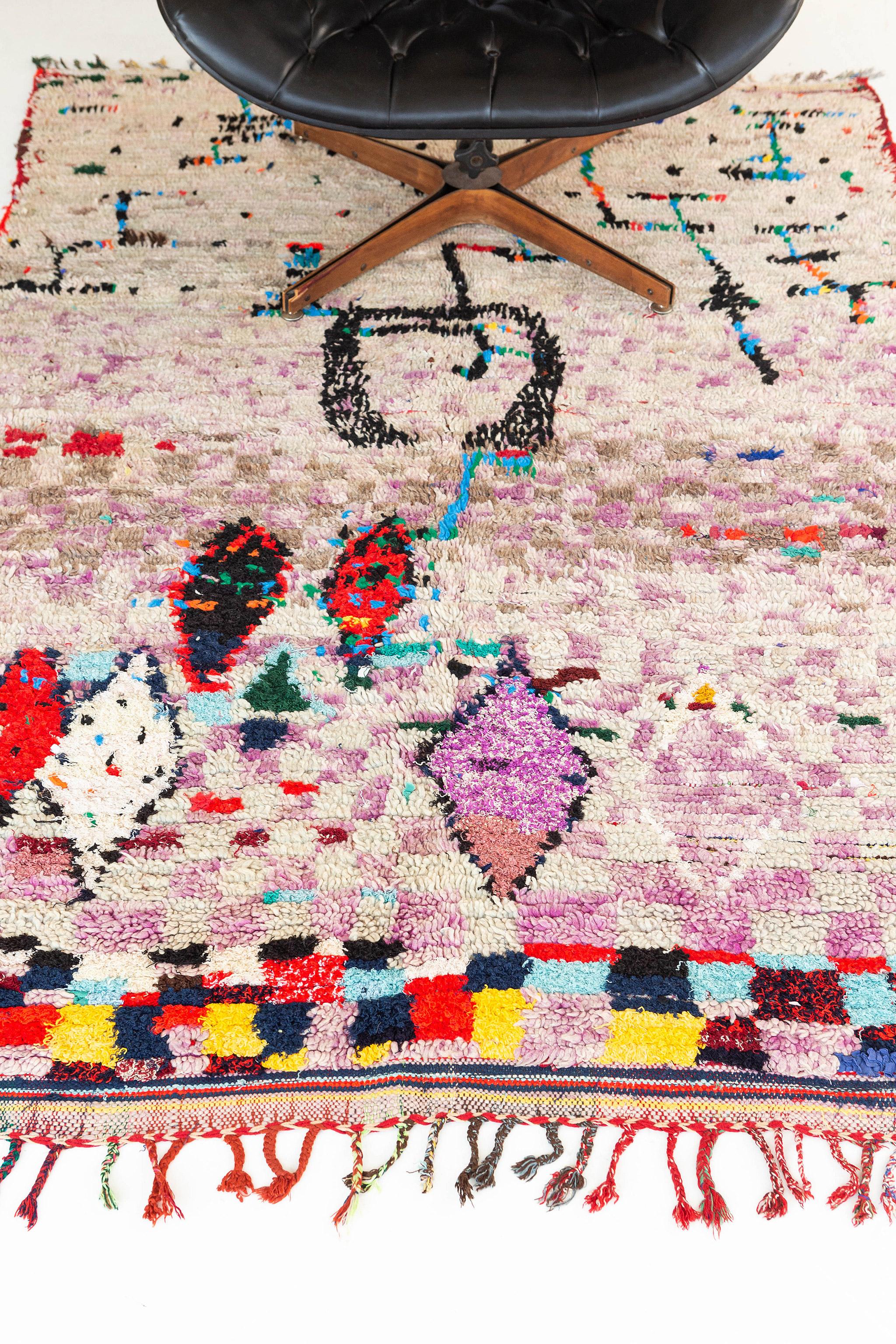 A rug like a painting. Abrash checkerboard ground runs throughout. The main area features alternating magenta-purple and ivory-gray colored squares, the top border introduces a riot of red, yellow, black, and turquoise. Field motifs draw from the