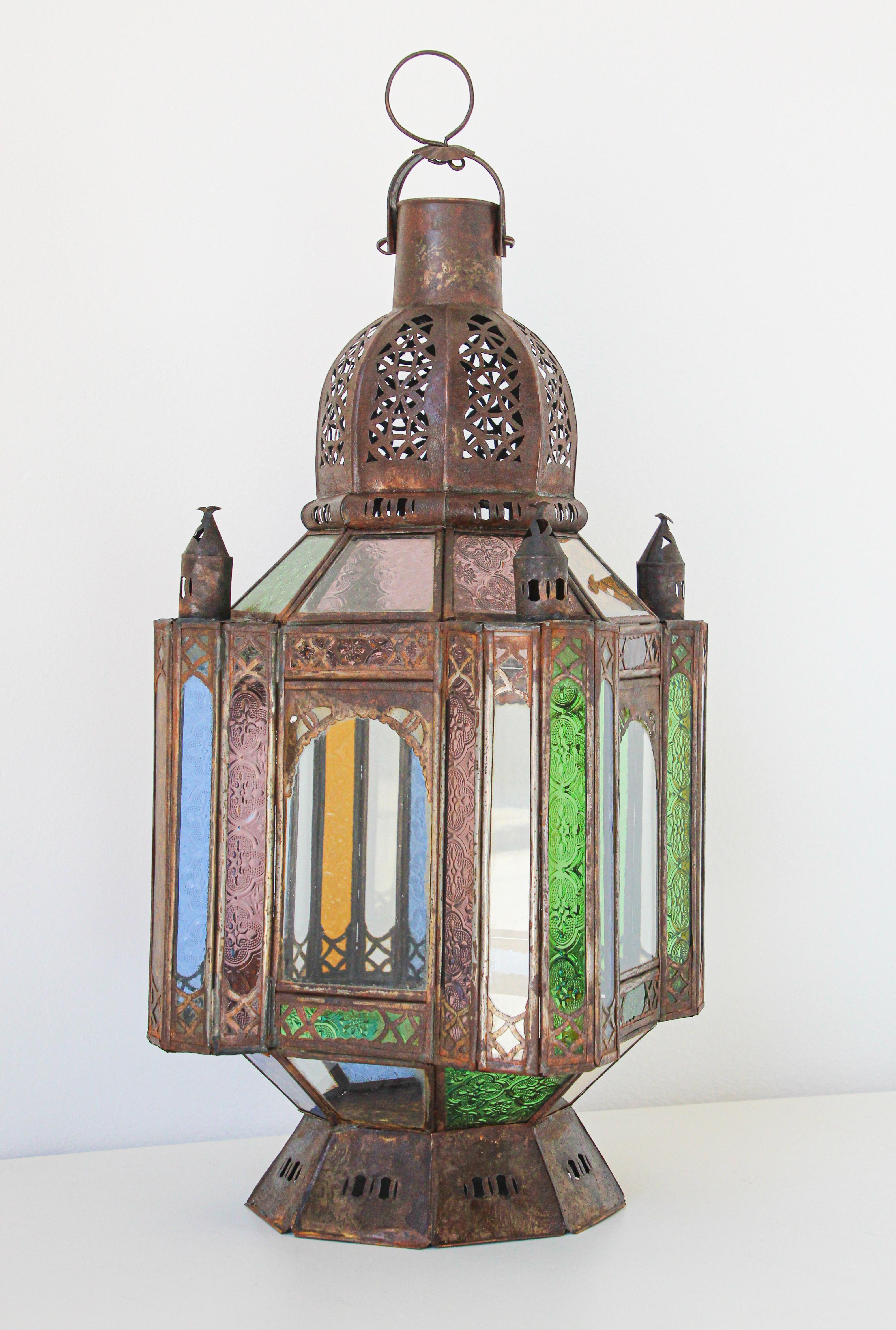 Handcrafted vintage Moroccan metal glass lantern or Moorish pendant.
Moorish style North African lantern with multi-color molded colored glass panels in green, lavender, blue and clear.
Hurricane candle lamp handmade in Marrakech, vintage metal in