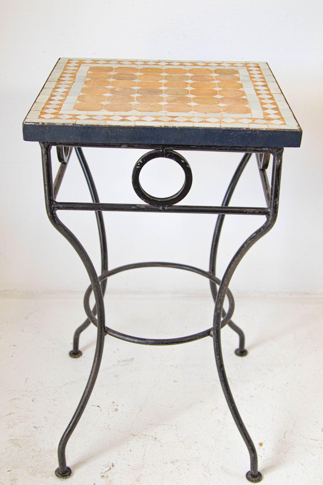 Vintage Marokkanische Mosaikfliesen Tisch im Freien.
Quadratischer Bistrotisch mit marokkanischen Mosaikfliesen auf einem Eisengestell.
Handgefertigt von erfahrenen Kunsthandwerkern in Fez, Marokko, unter Verwendung von alten glasierten Elfenbein-
