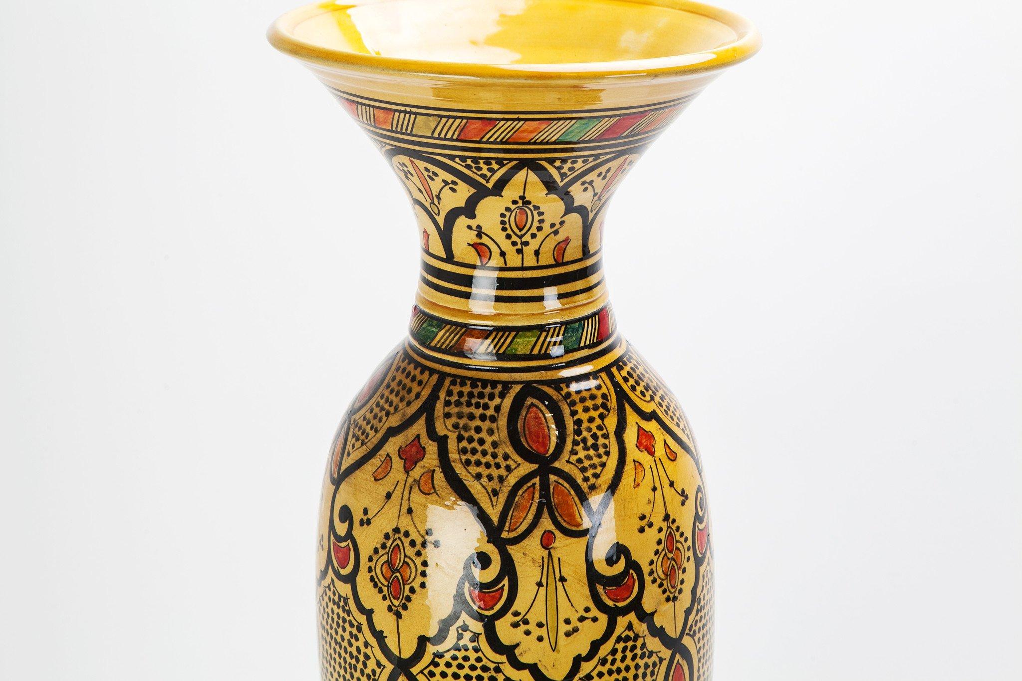 Avec son intrigante forme conique, ses couleurs rustiques absorbantes (jaune, orange et noir) et son motif richement orné, ce vase vintage visuellement puissant, fabriqué à la main, est l'ajout idéal à toute pièce en quête d'élégance exotique. Le