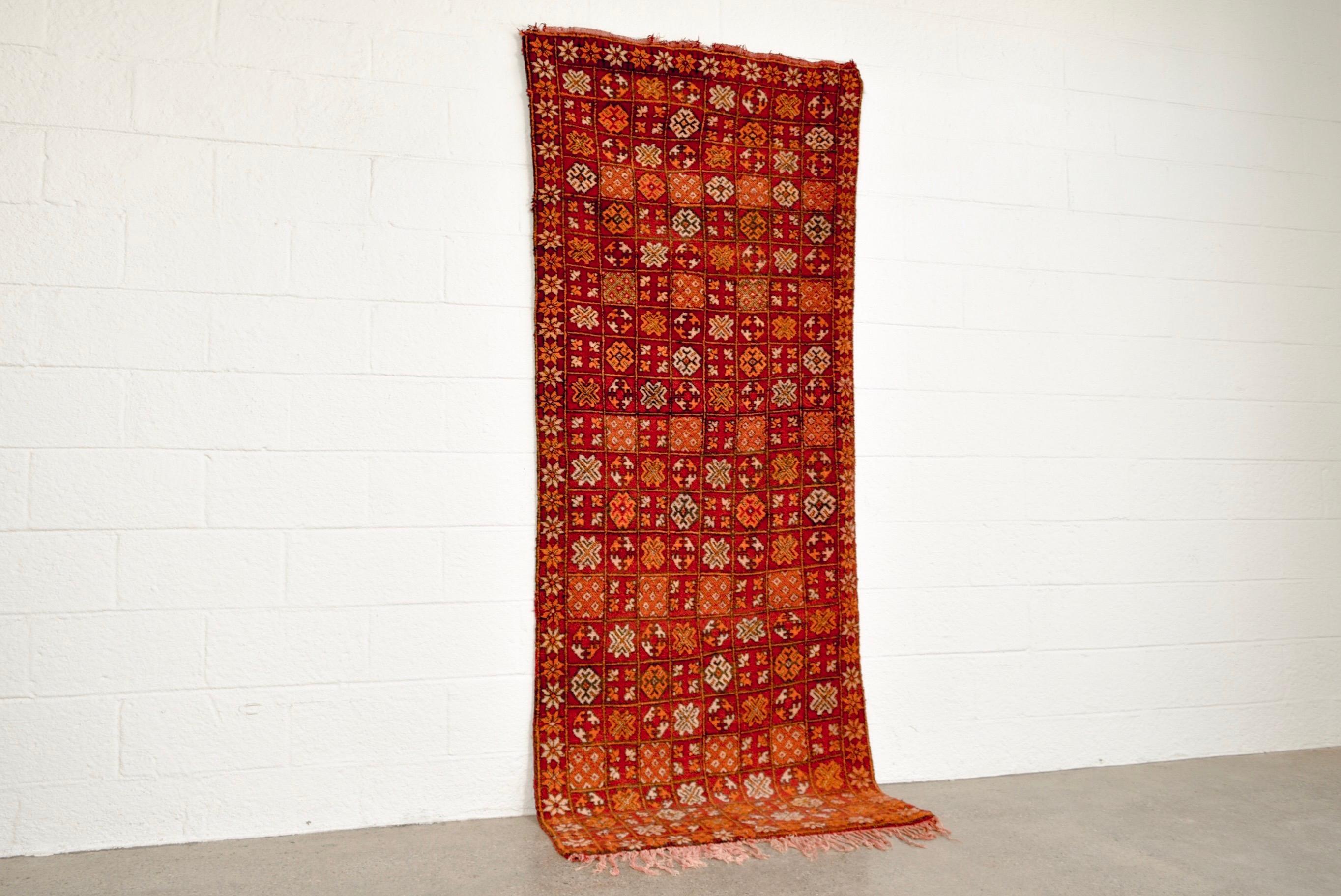 This rich and vibrant vintage handwoven Moroccan Boujad rug runner features an overall geometric pattern composed of a grid of intricate lozenges with smaller squares, pointed stars, crosses and other Berber symbolism. With a soft, low pile texture,