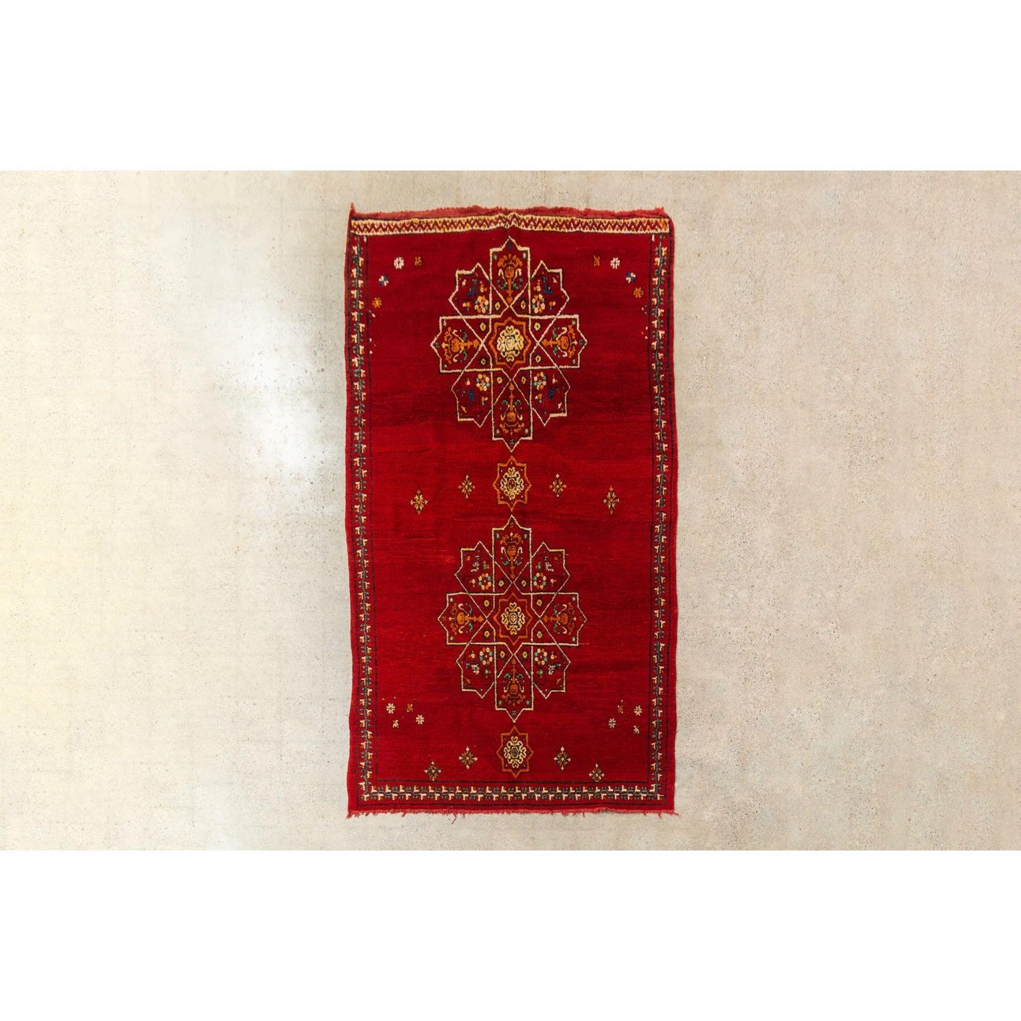 This stunning large vintage handwoven Moroccan Berber rug circa Mid-20th Century is a beautiful combination of hand knotted pile and embroidery. The design features a large symmetrical arabesque pattern on a gorgeous field of crimson red with accent