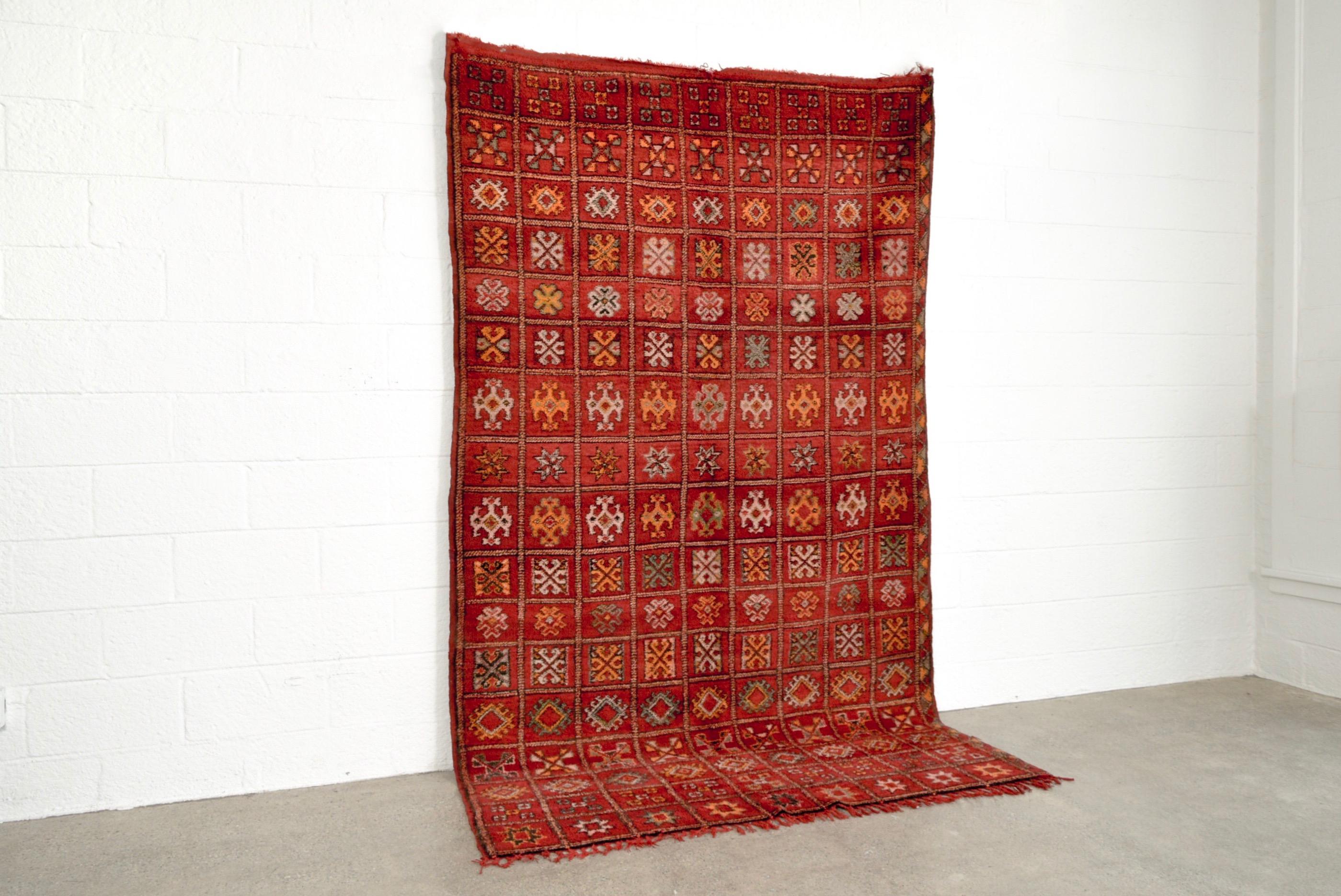 Dieser reiche, handgewebte marokkanische Boujad-Teppich weist ein geometrisches Gesamtmuster auf, das sich aus einem Raster aus verschlungenen Rauten mit kleineren Quadraten, spitzen Sternen, Kreuzen und anderen Berbersymbolen zusammensetzt. Der