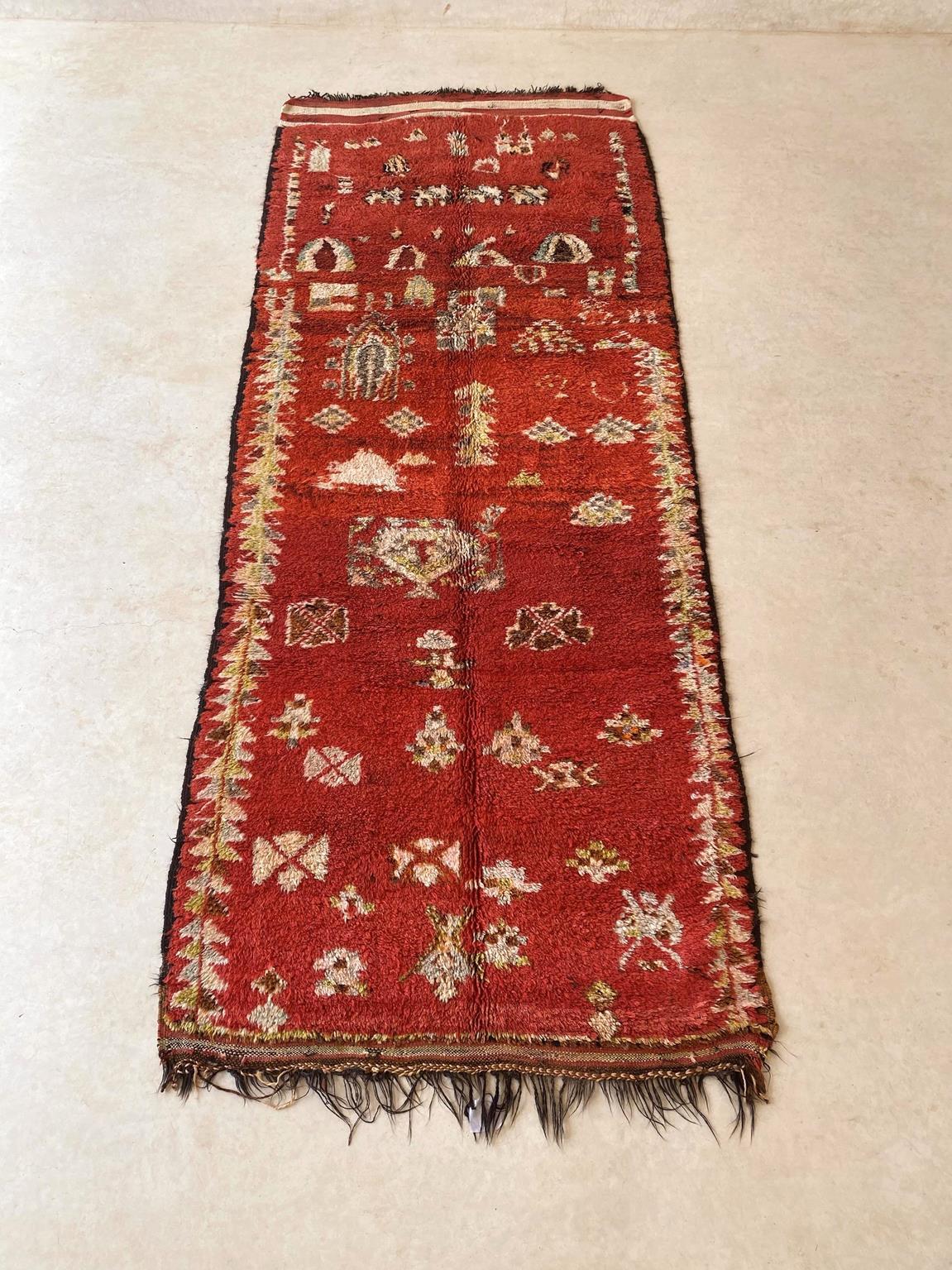 Here is one very beautiful, unique vintage rug, probably from the Rehamna tribe. The background is a deep red with yellow green, brownish, gray and cream designs like diamonds, crosses and scales and others that are open to interpretations. It shows