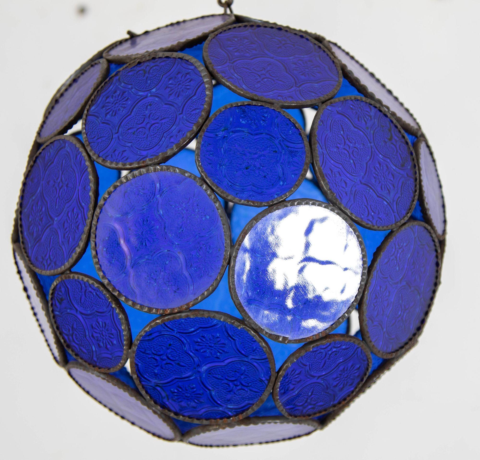 Handcrafted Moroccan cobalt blue glass lantern or Moorish pendant.
Cobalt blue molded glass color with Moorish design circles put together in an orb style lamp.
Handmade in Marrakech, metal rust color finish, colorful multifaceted orb glass