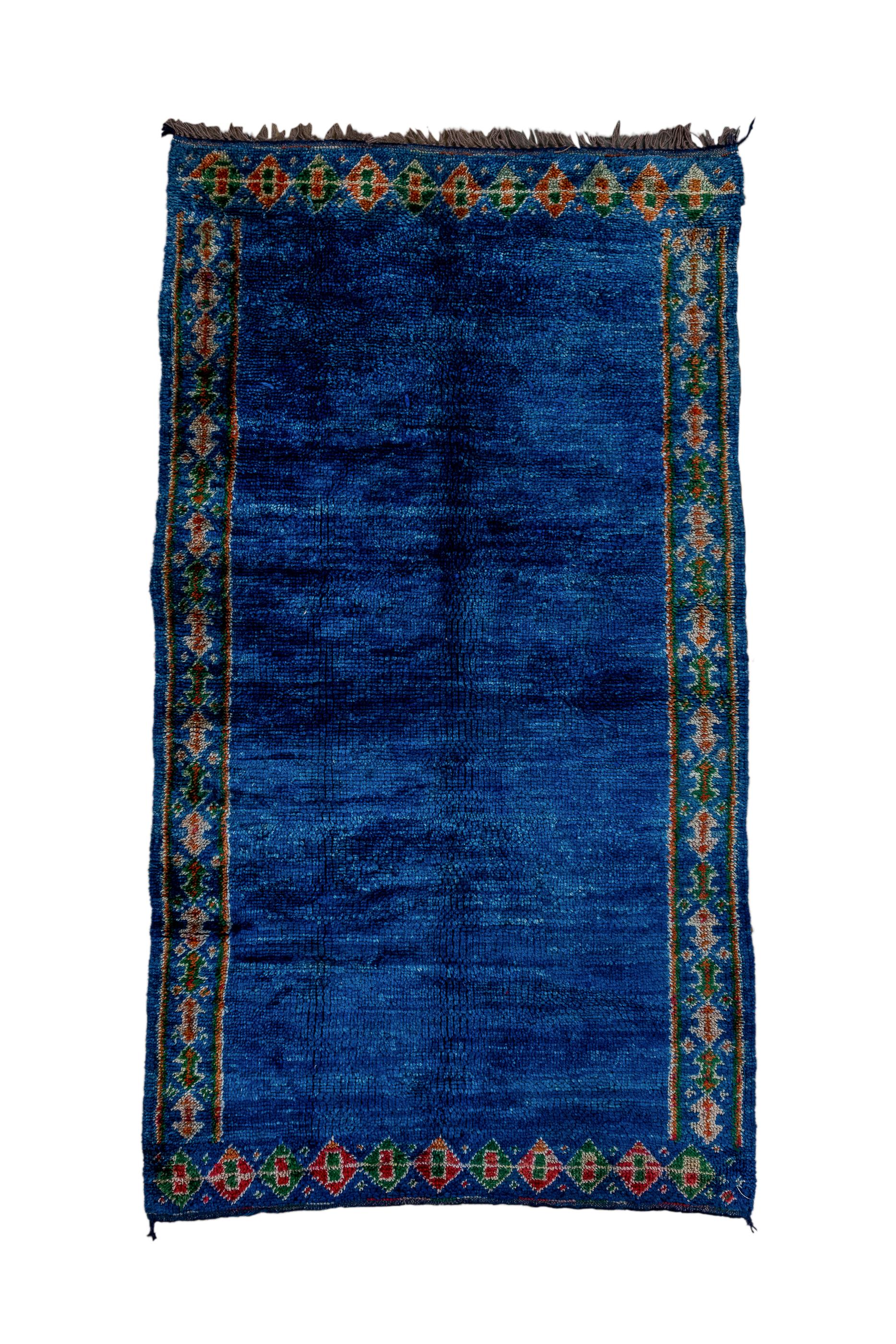 The open, royal blue abrashed and radiant field is neatly framed by the equally blue border of doubled arrowheads in the Turkish manner. From the Moroccan lowlands. Coarse weave. All wool and long pile. Good condition.
  