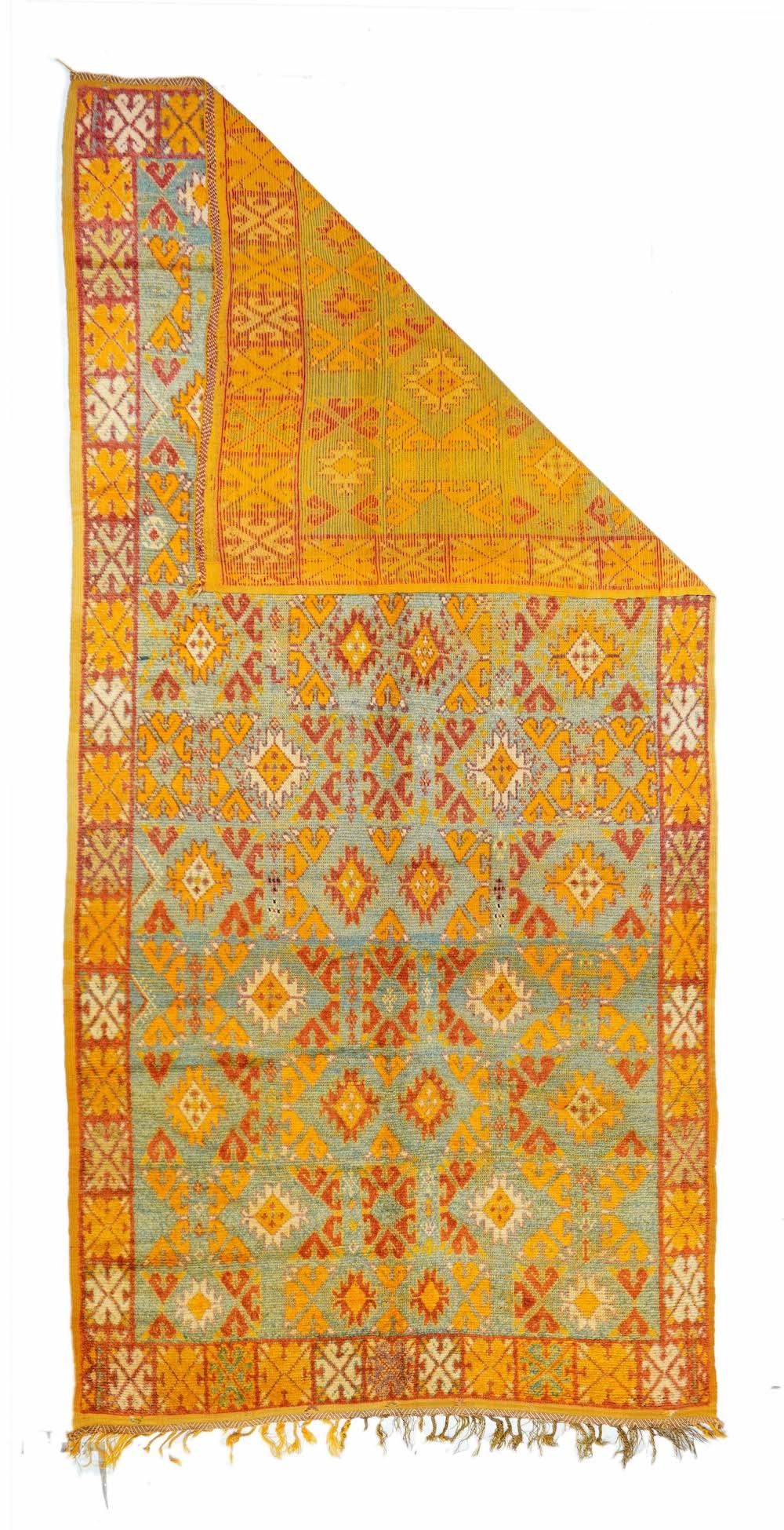 Vintage Moroccan Rug 4'8'' x 9'8''. The distinctly abrashed light to pale blue field shows ten staggered rows of ashiks and quadruple pairs of Vees, with narrow red borders with fliate crosses. Detail tones of: goldenrod, rust-red and ecru. Coarse