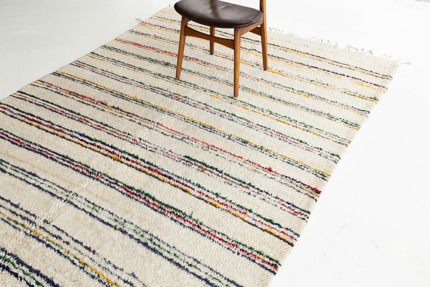 A charming vintage Moroccan rug made by the Azilal tribe of Morocco. Beautiful multicolored stripes atop an ivory pile weave make for the perfect contemporary piece. Azilal rugs originating from the high Atlas mountains contain much symbolism and